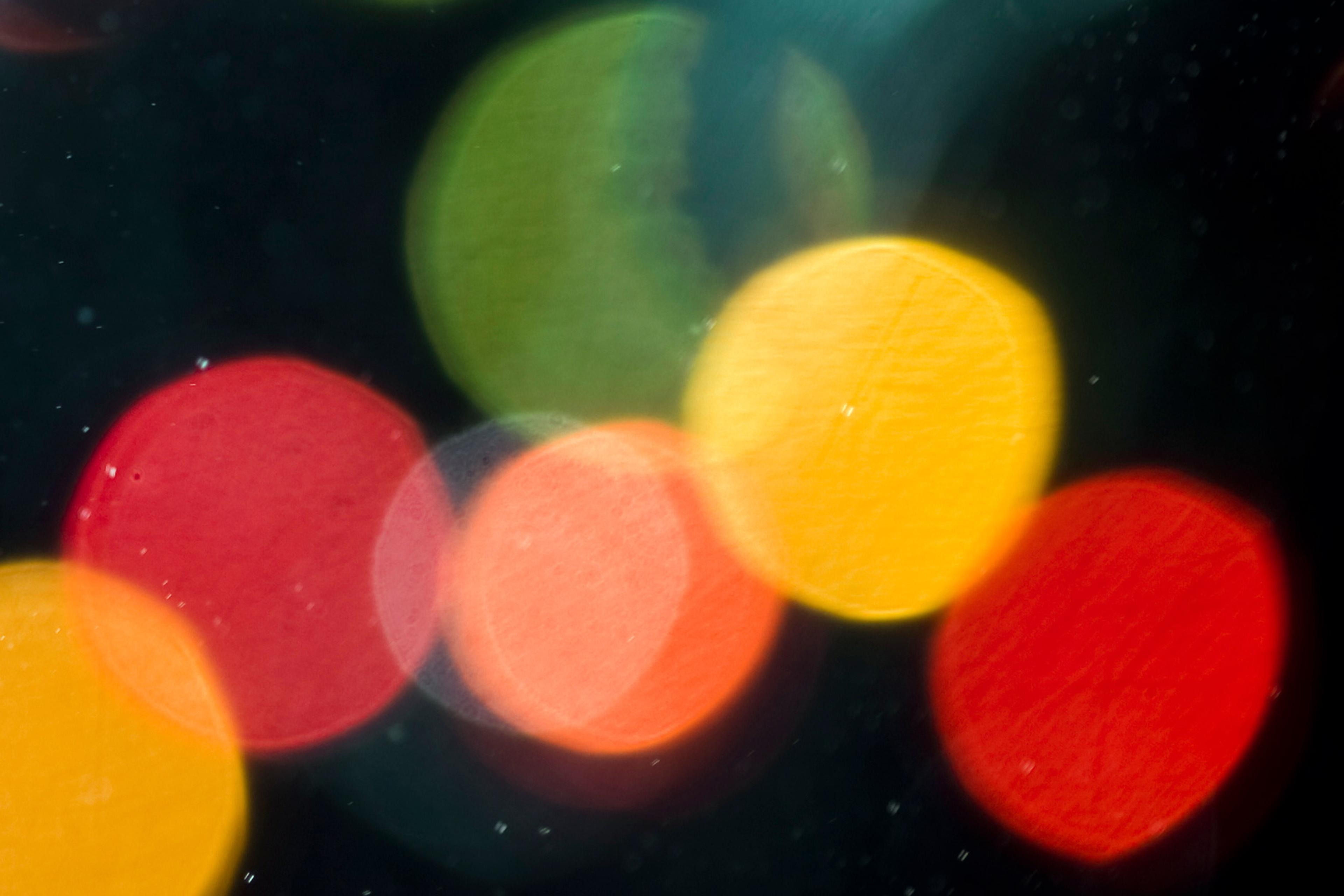 Abstract photo of colourful bokeh lights in red, green and yellow on a dark background.