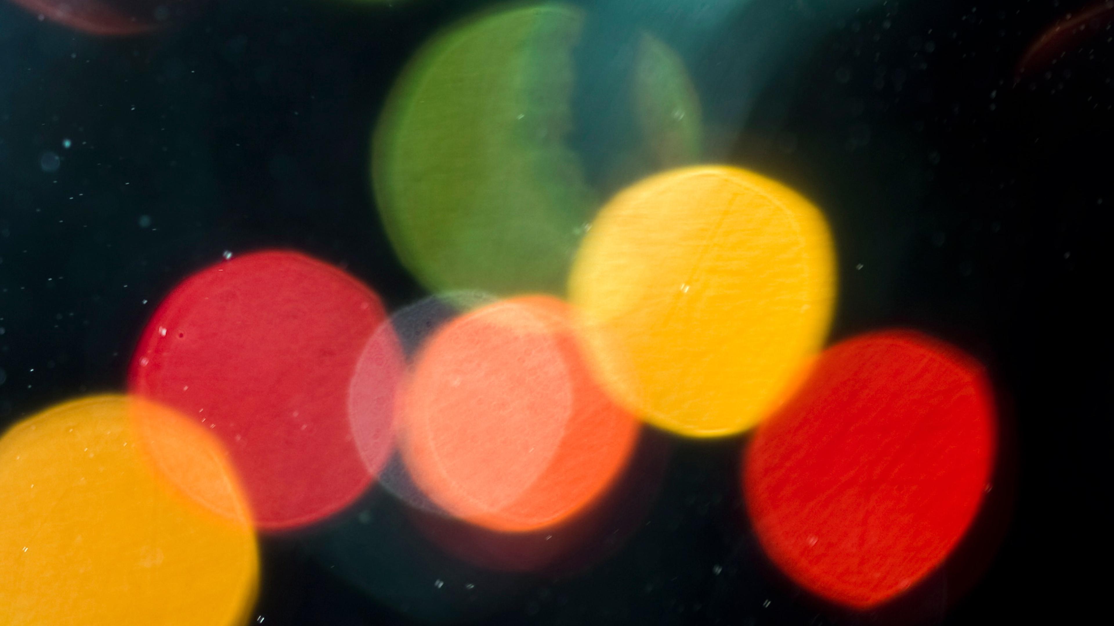 Abstract photo of colourful bokeh lights in red, green and yellow on a dark background.