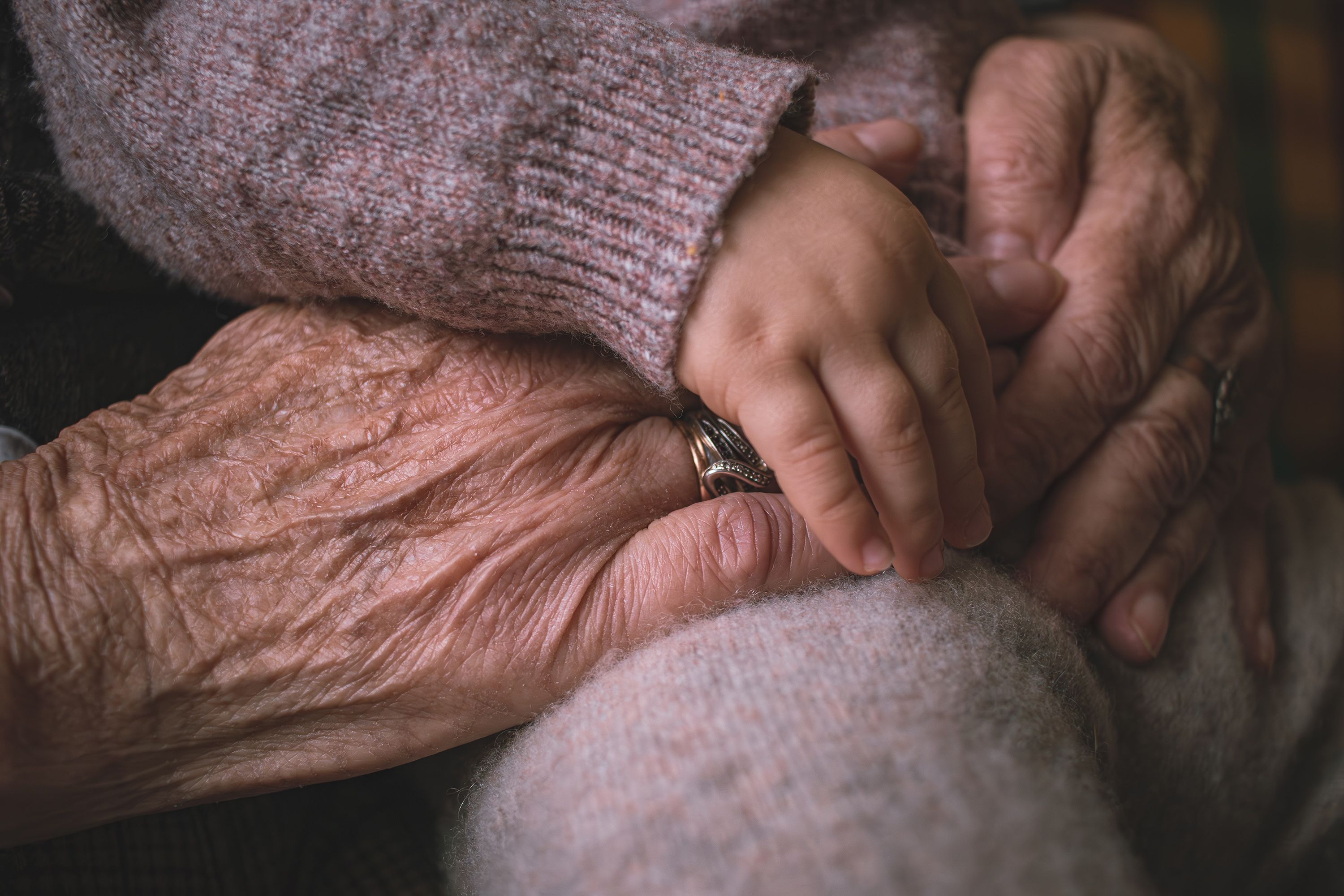 A child’s hand resting on an elderly person’s hands.
