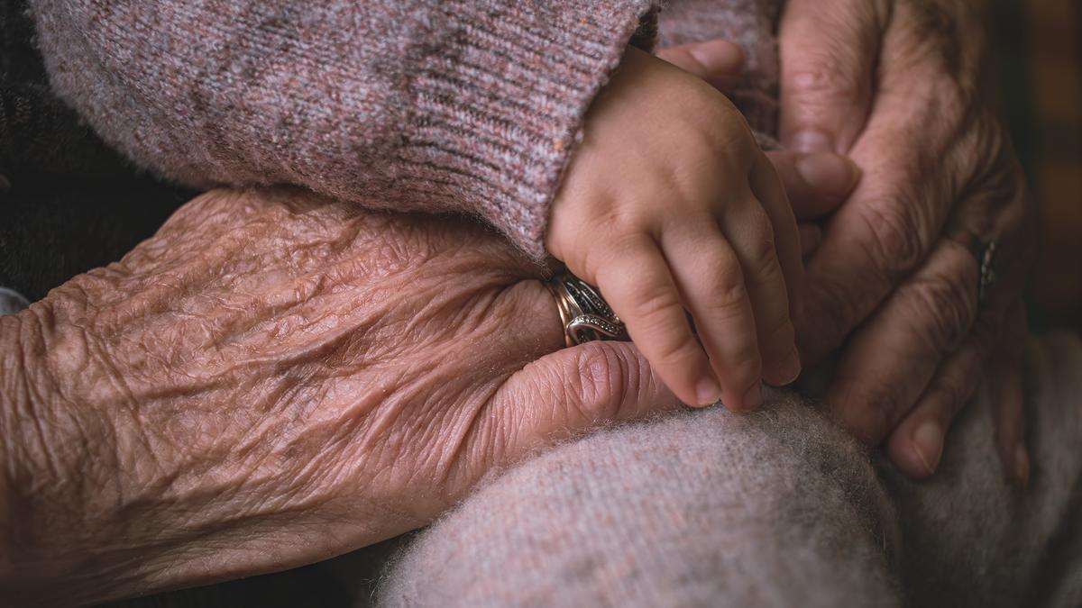 A child’s hand resting on an elderly person’s hands.