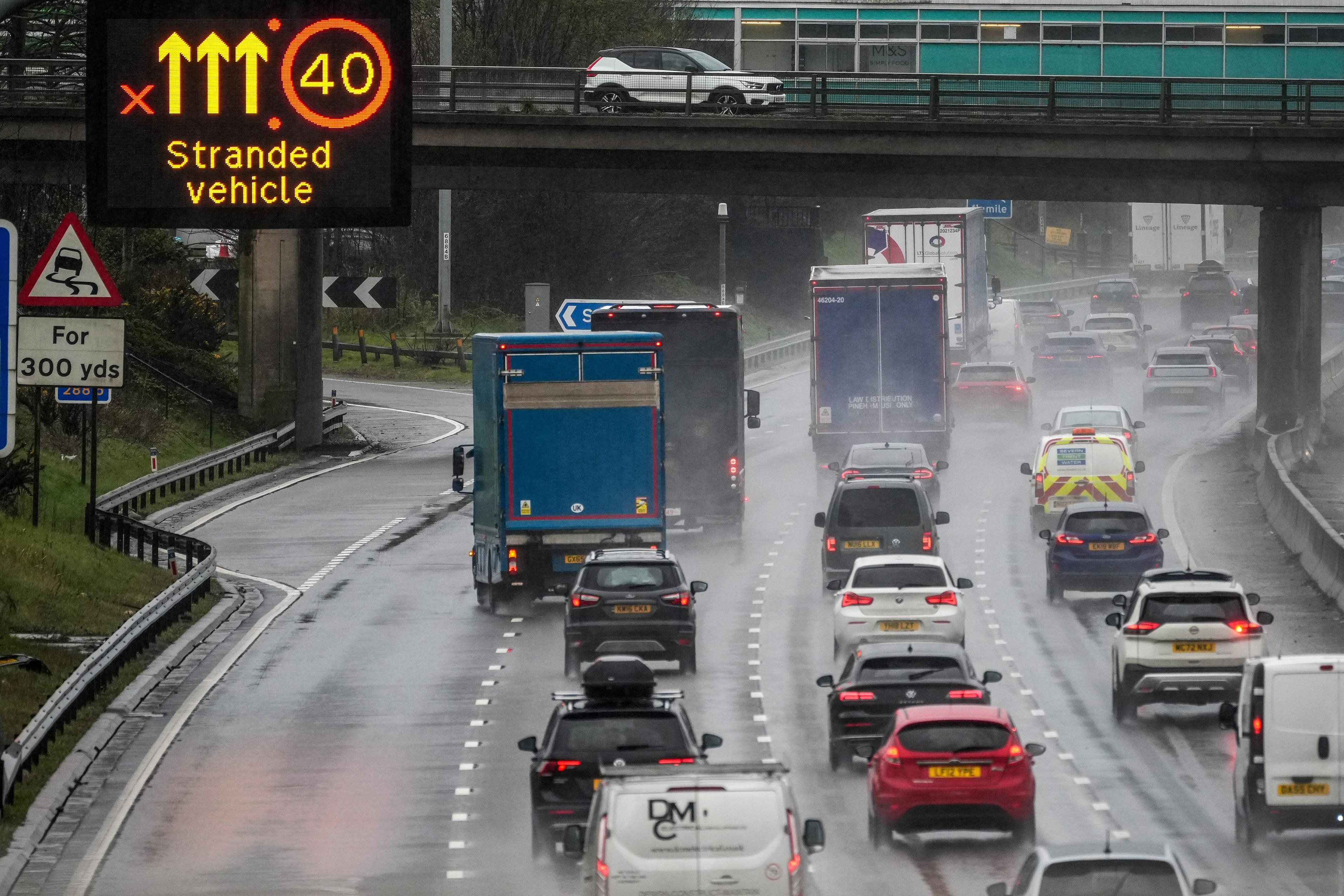 Photo of a rainy motorway with heavy traffic and a sign warning of a stranded vehicle, speed limit 40 mph.