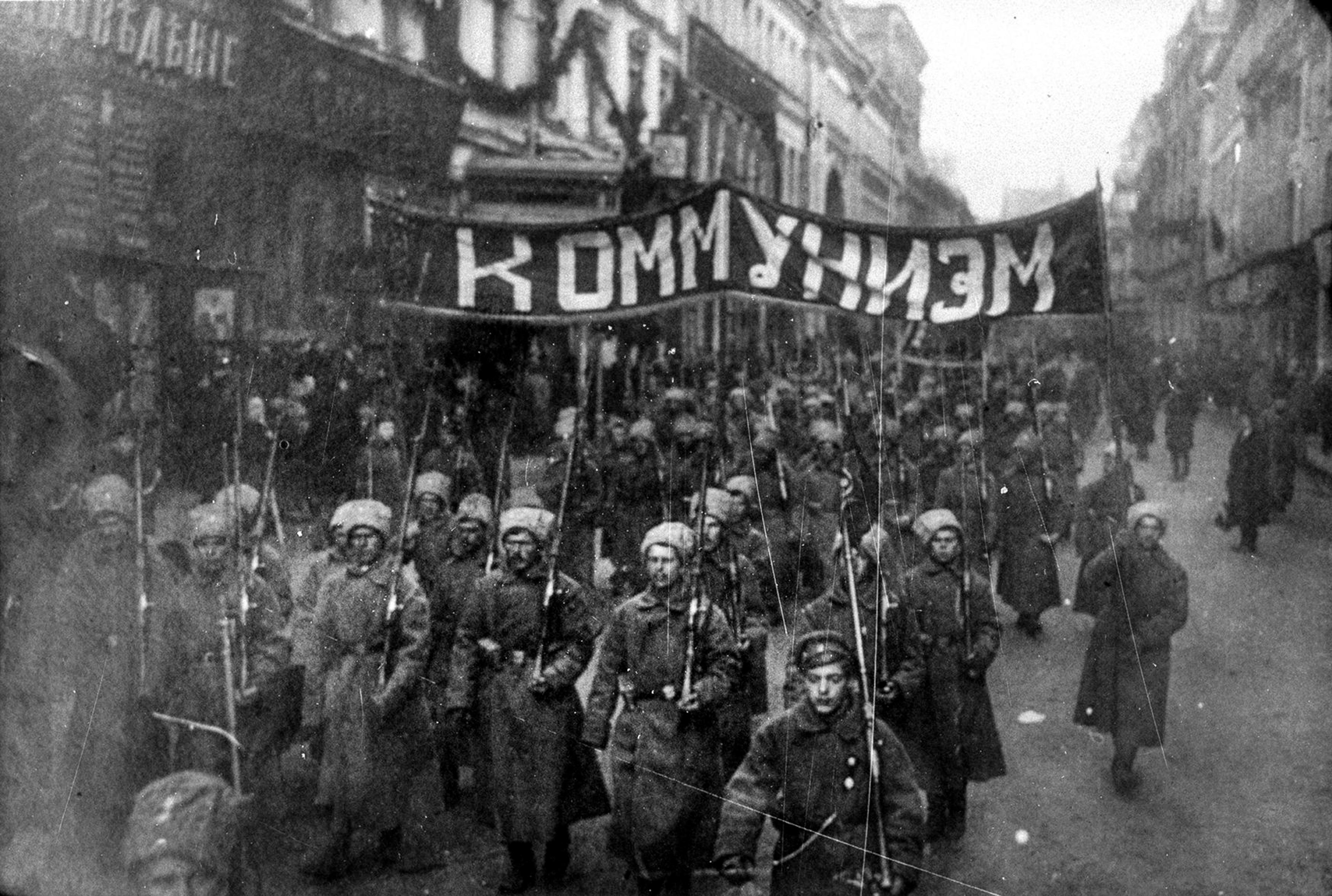 <p>Armed soldiers carry a banner reading ‘Communism’ in Nikolskaya street, Moscow, October 1917. <em>Courtesy Wikipedia</em></p>