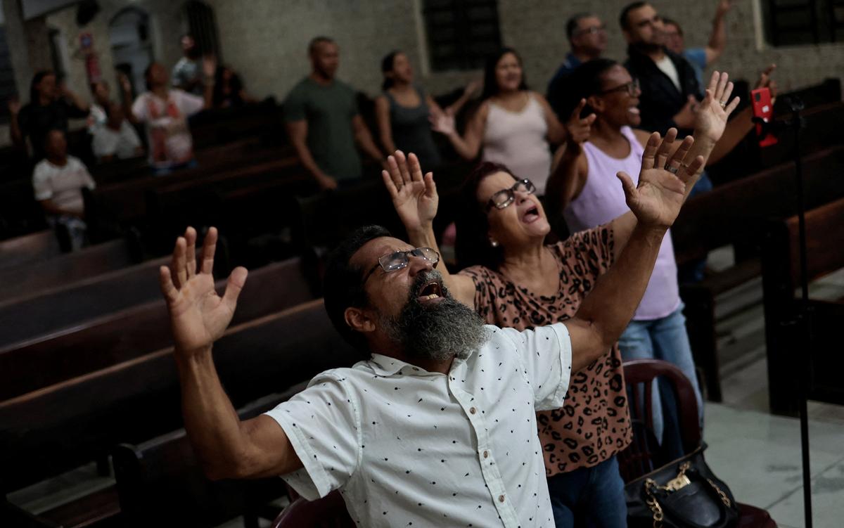 People in a church with raised hands in worship, expressions of joy and devotion on their faces.