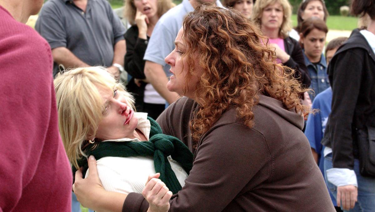 A woman is grappling with another woman who has a bloody nose