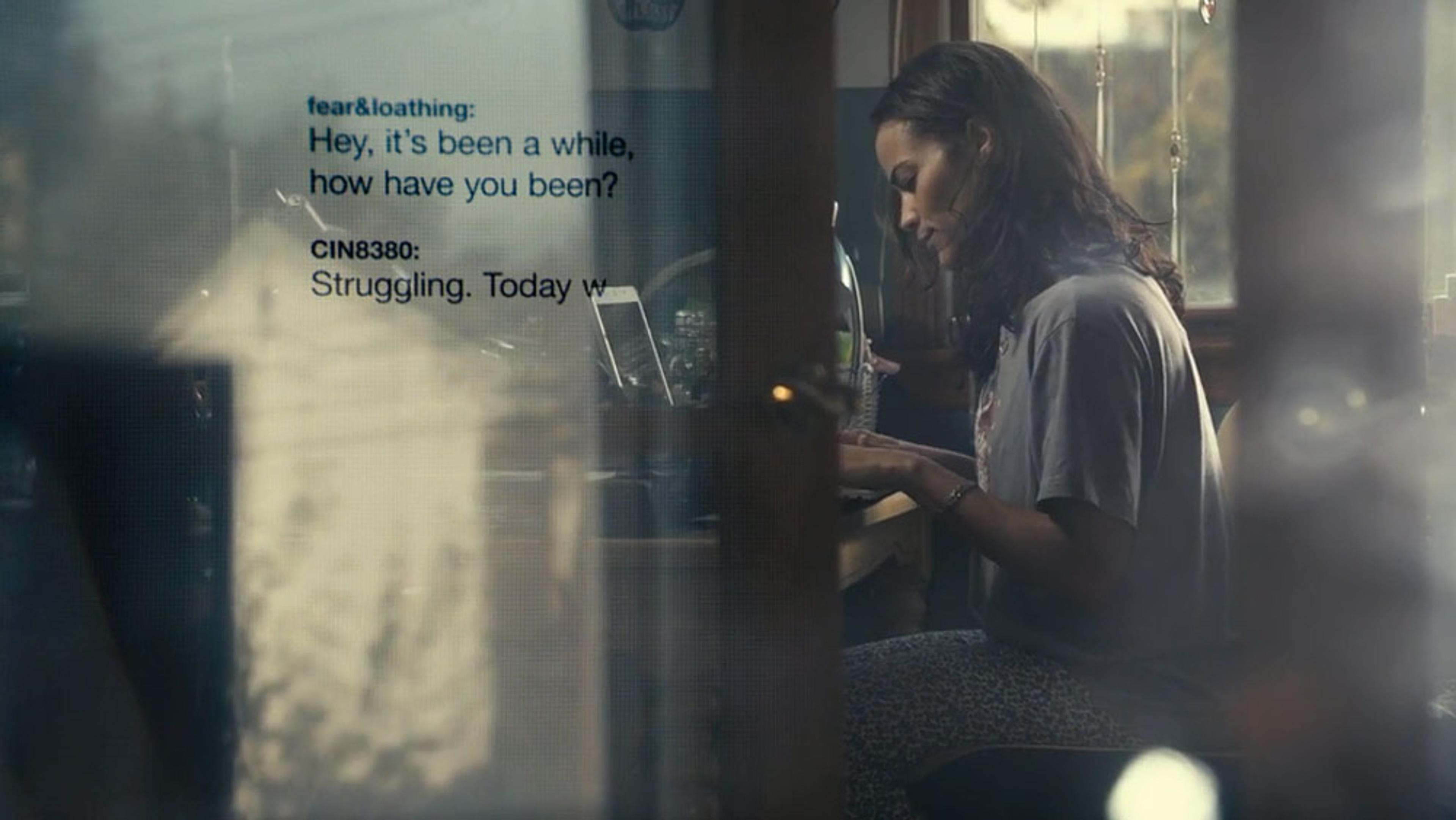 A woman typing on a laptop at a desk with a chat overlay showing a conversation about struggling and reconnecting.