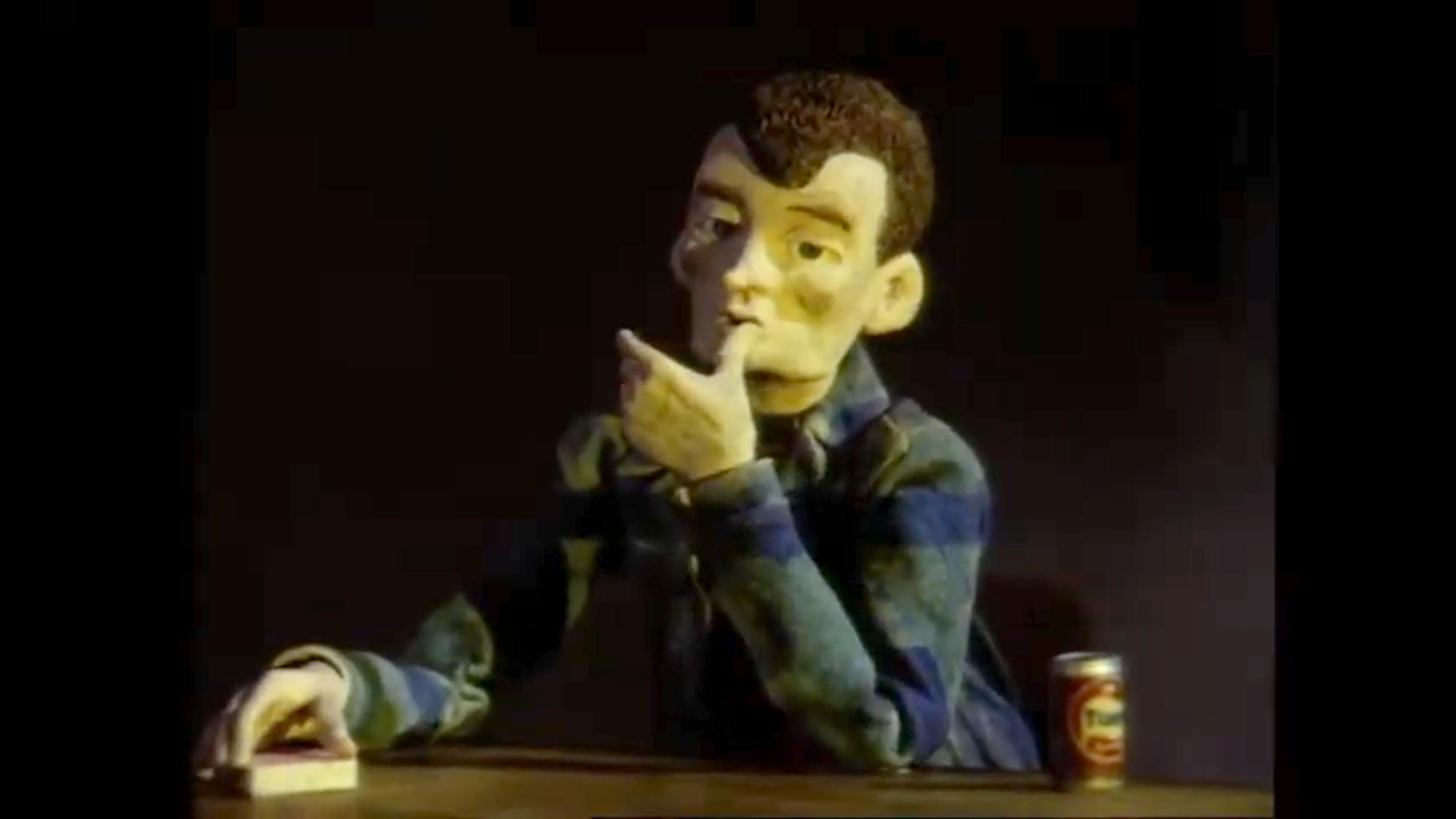 Clay animation of a person pondering at a table with a drink can, against a dark background.