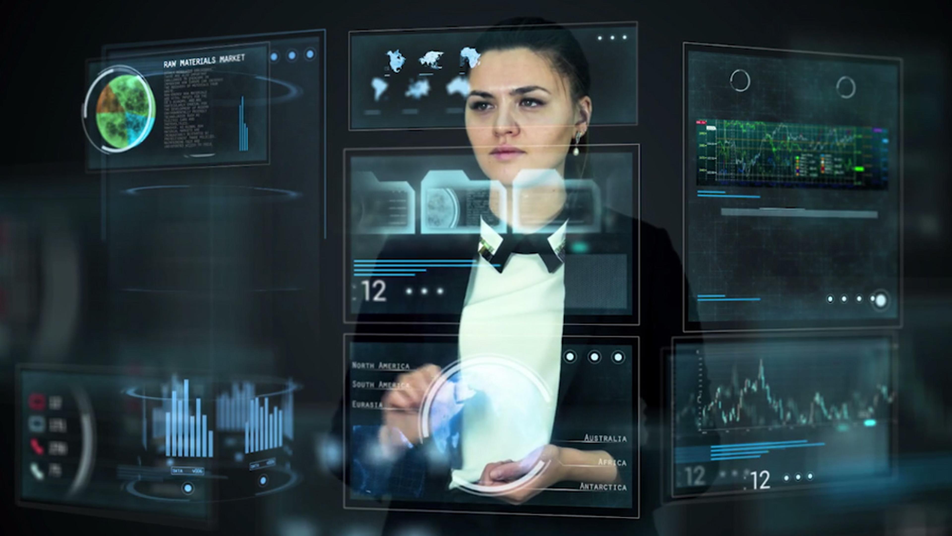 A woman using futuristic transparent touchscreen interfaces displaying graphs, maps and data in a dark environment.