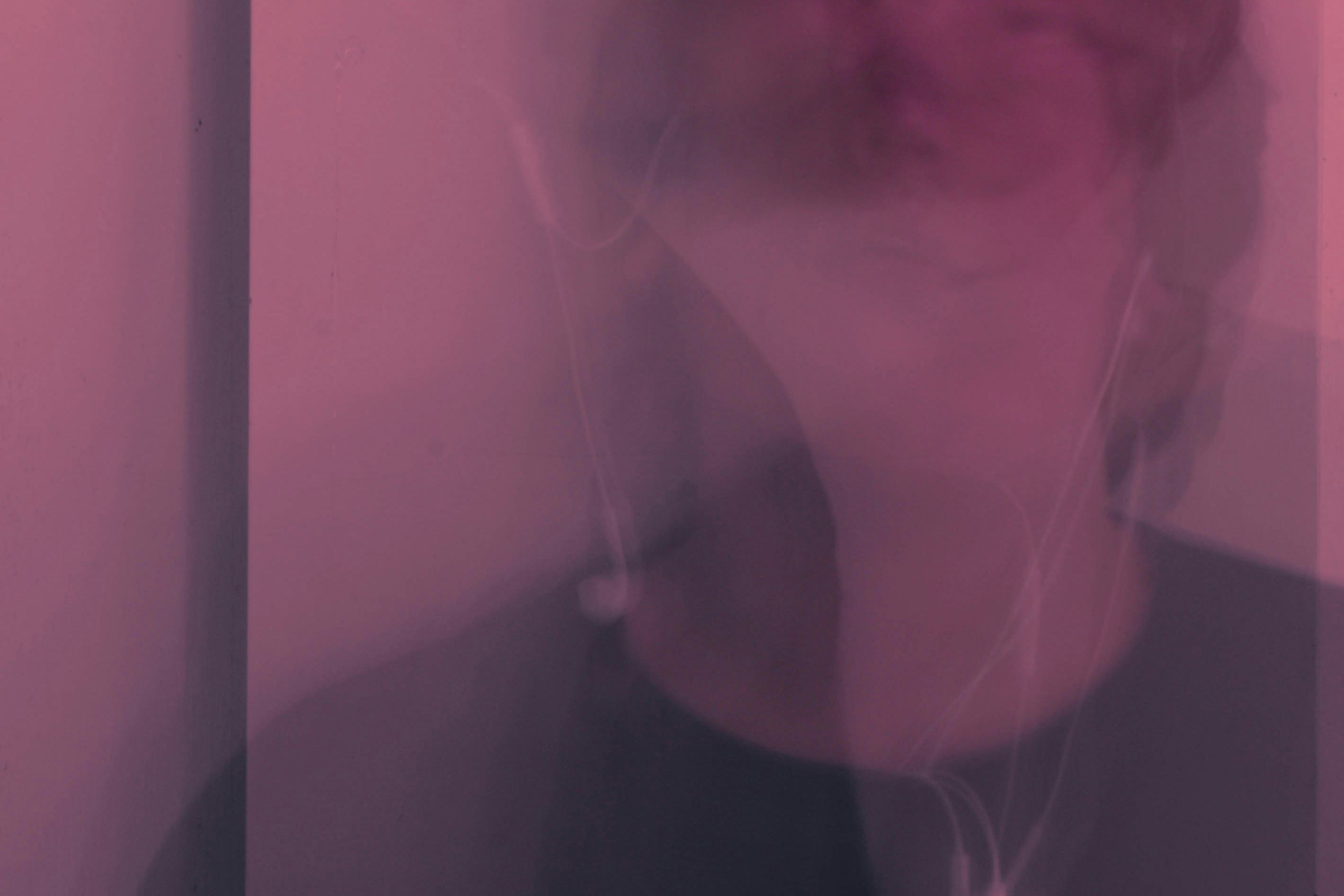 Abstract photo with a pink hue showing a blurred face and earphones.