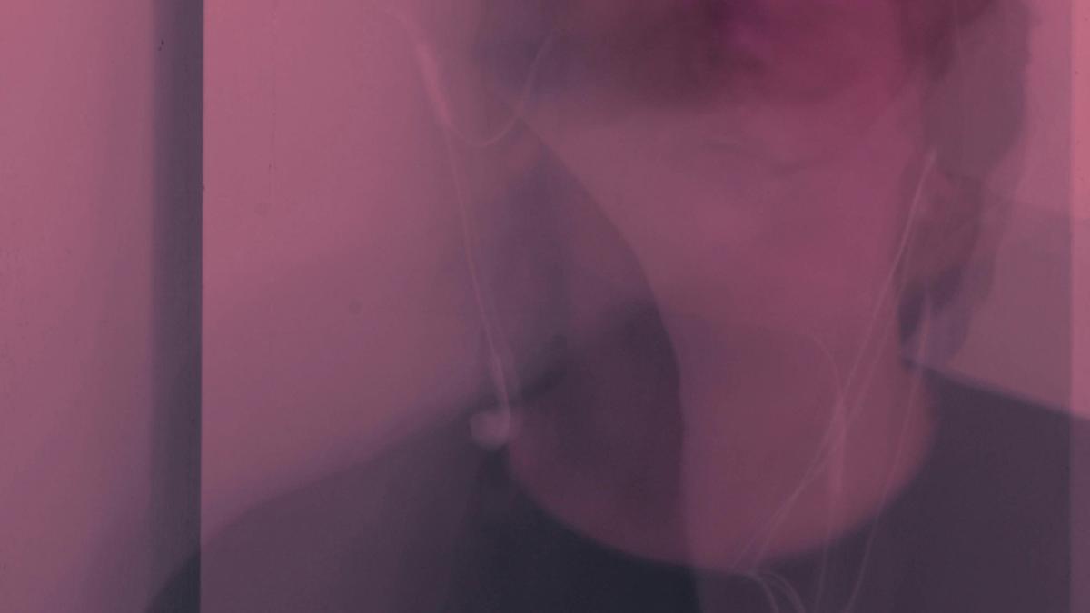 Abstract photo with a pink hue showing a blurred face and earphones.