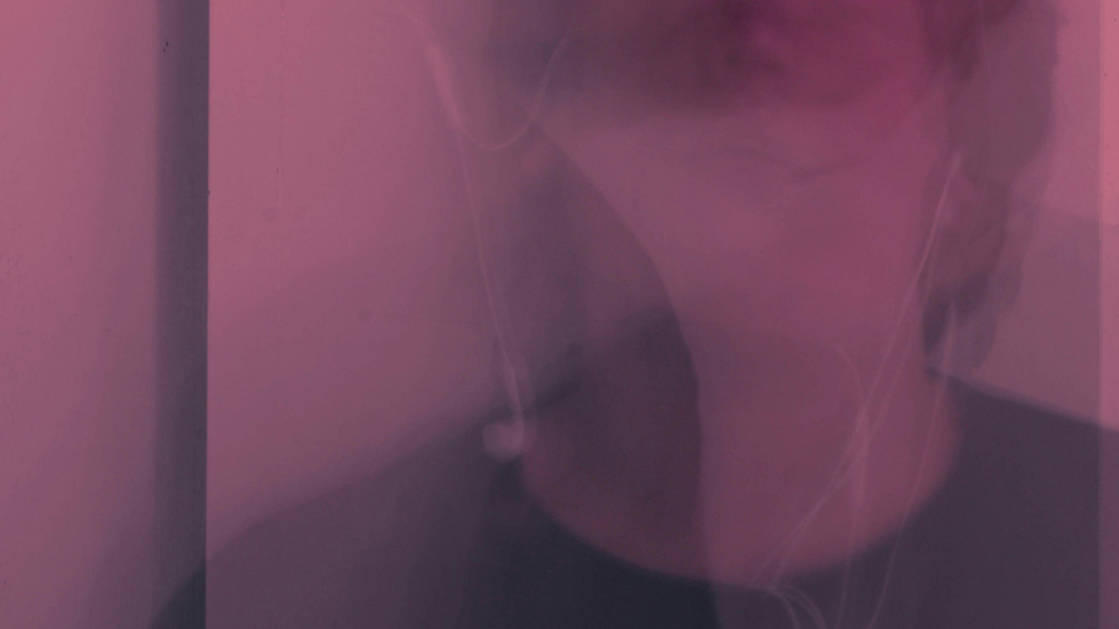 Abstract photo with a pink hue showing a blurred face and earphones.