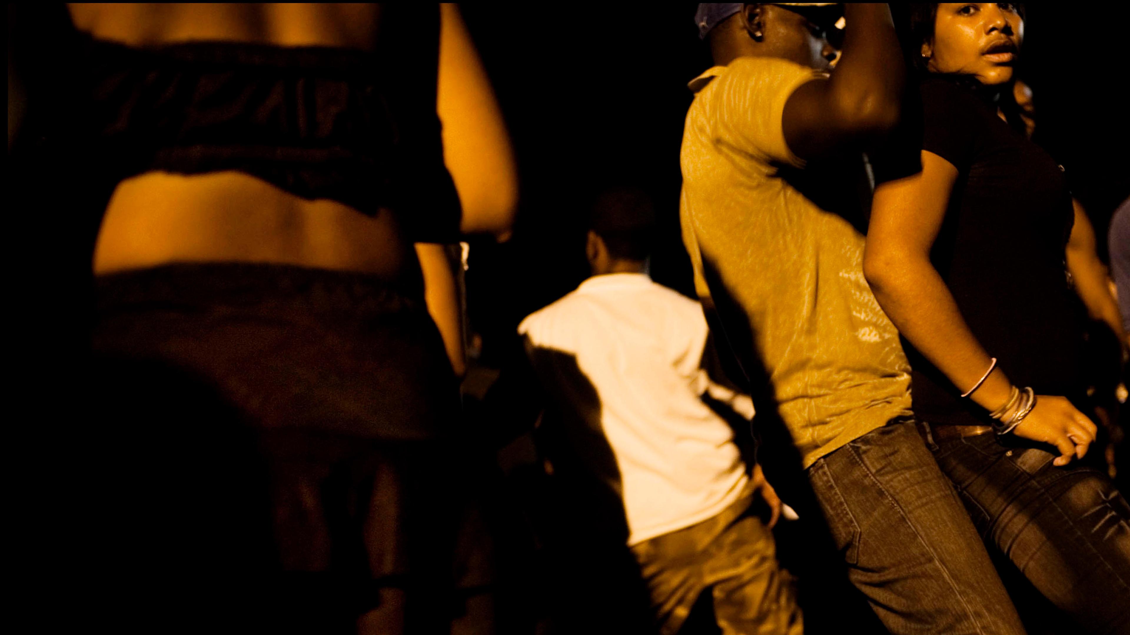 People dancing closely in dim lighting. The focus is on movement and atmosphere at a night event.