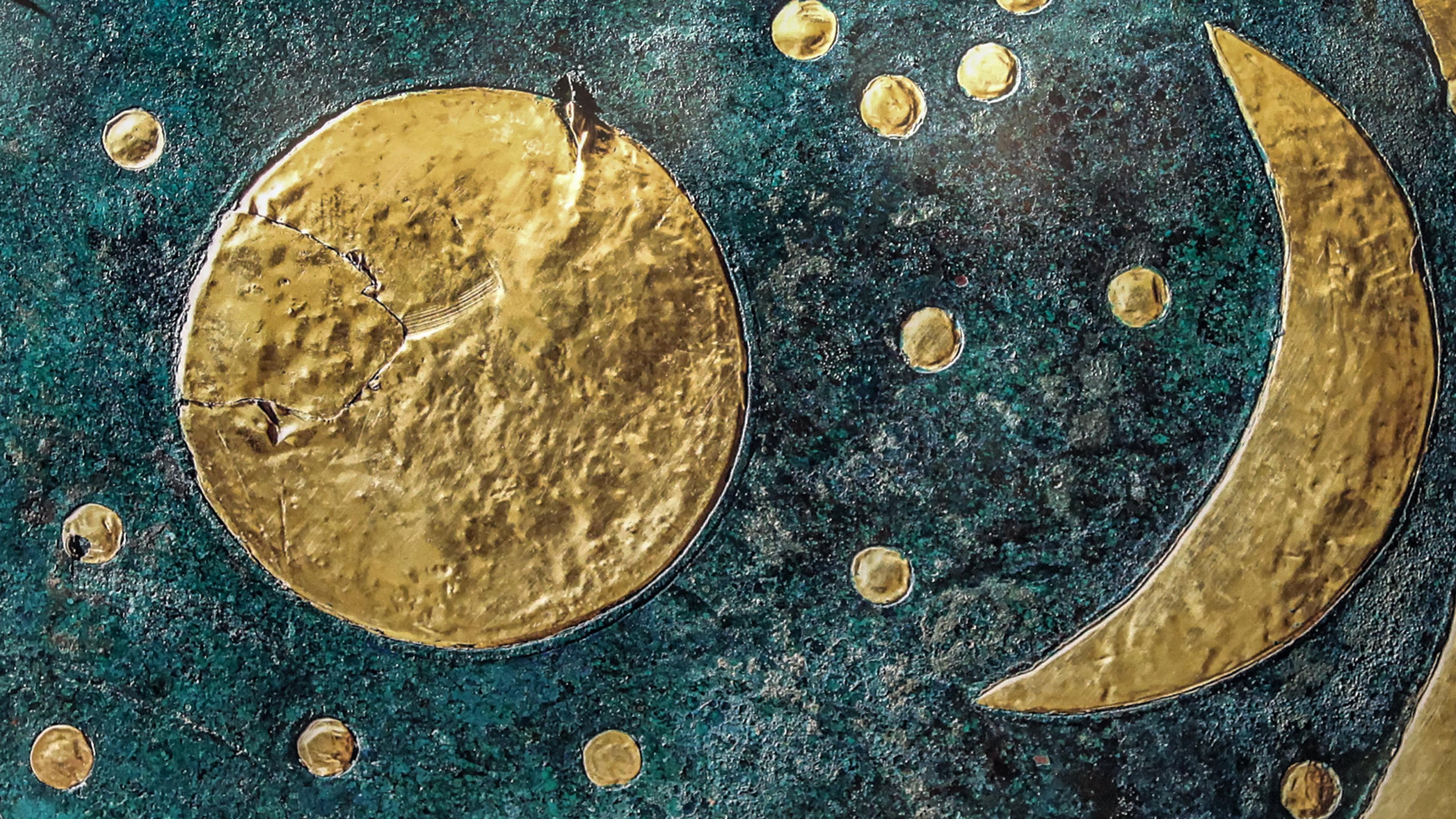 Ancient artefact with gold sun, moon, and stars on a dark blue-green background, likely depicting an early astronomical observation.