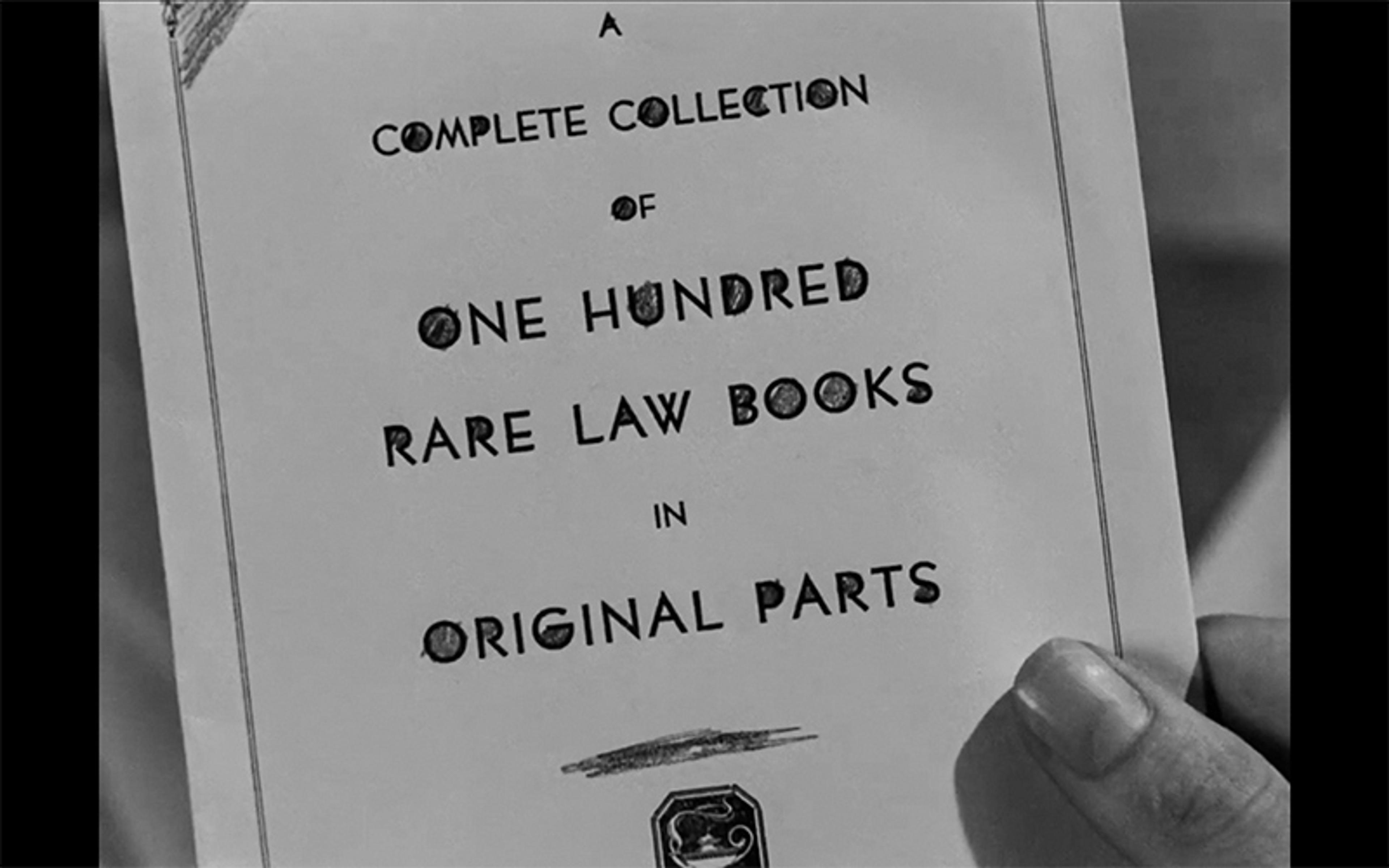 Black and white photo of a hand holding a page titled “A Complete Collection of One Hundred Rare Law Books in Original Parts”.
