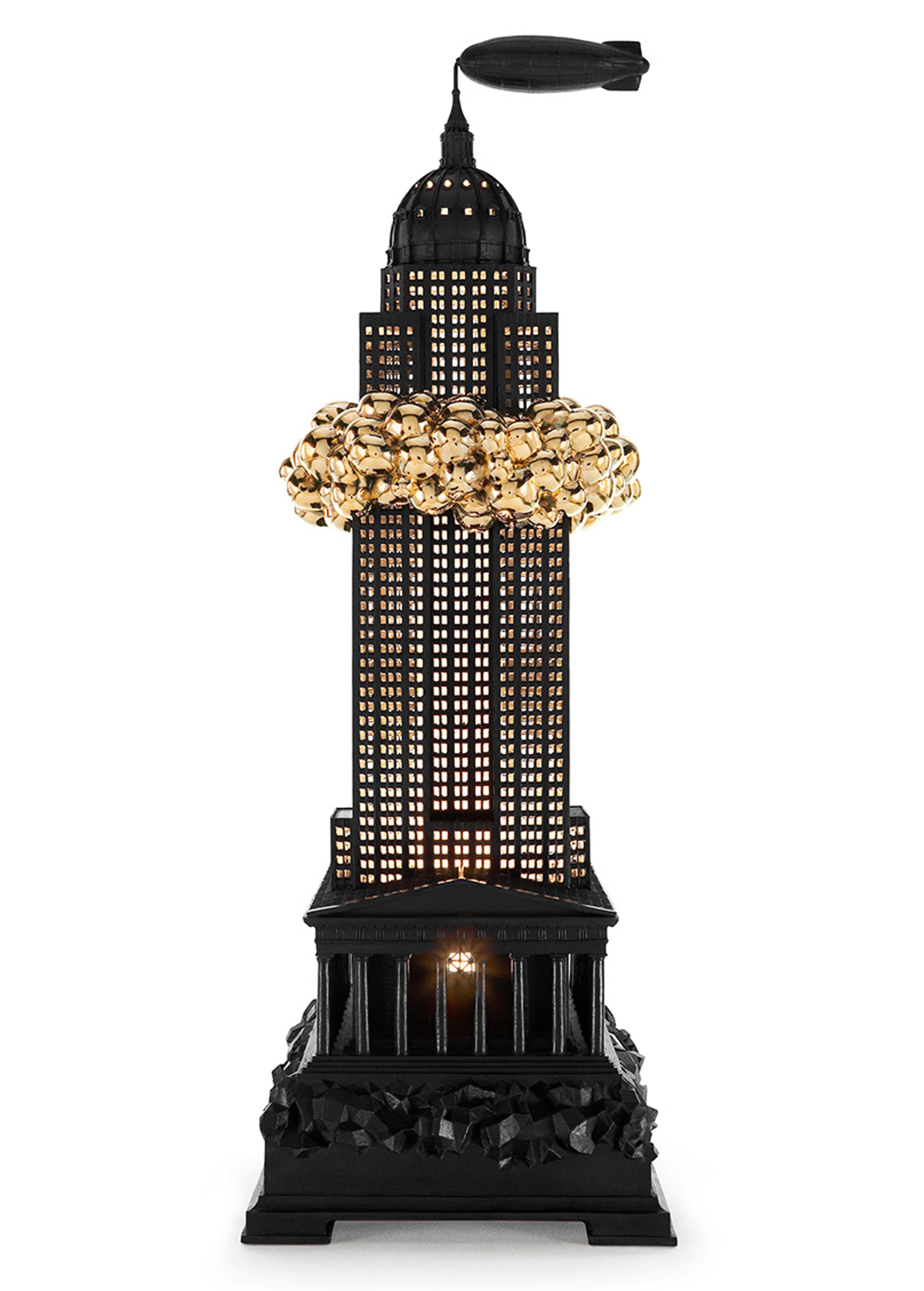 3D sculpture of a black skyscraper with golden figures climbing around its middle and an airship floating above the spire.