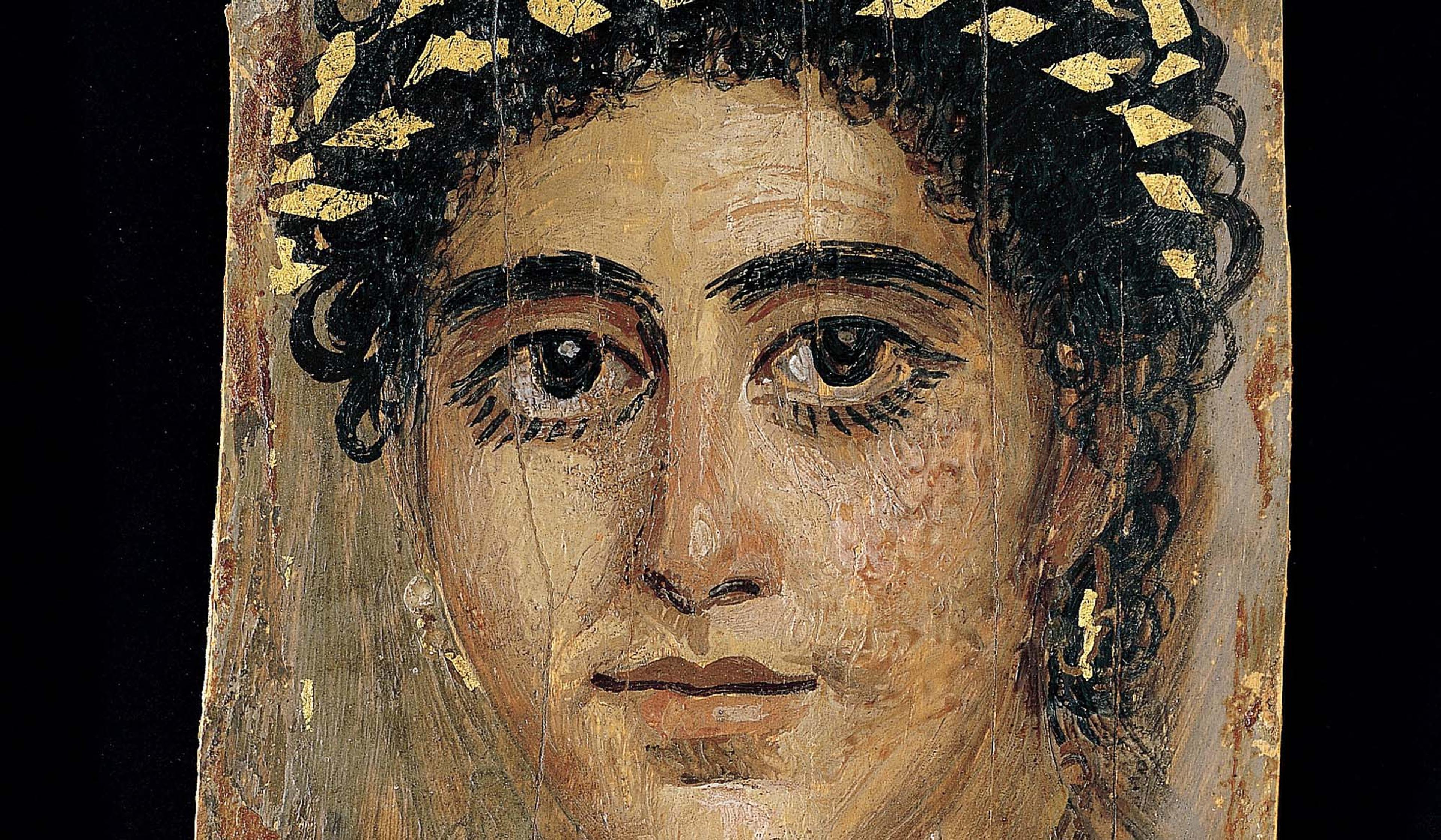 A painting of a woman’s face with curly hair, large eyes and a gold leaf wreath against a dark background. The image is worn and cracked.