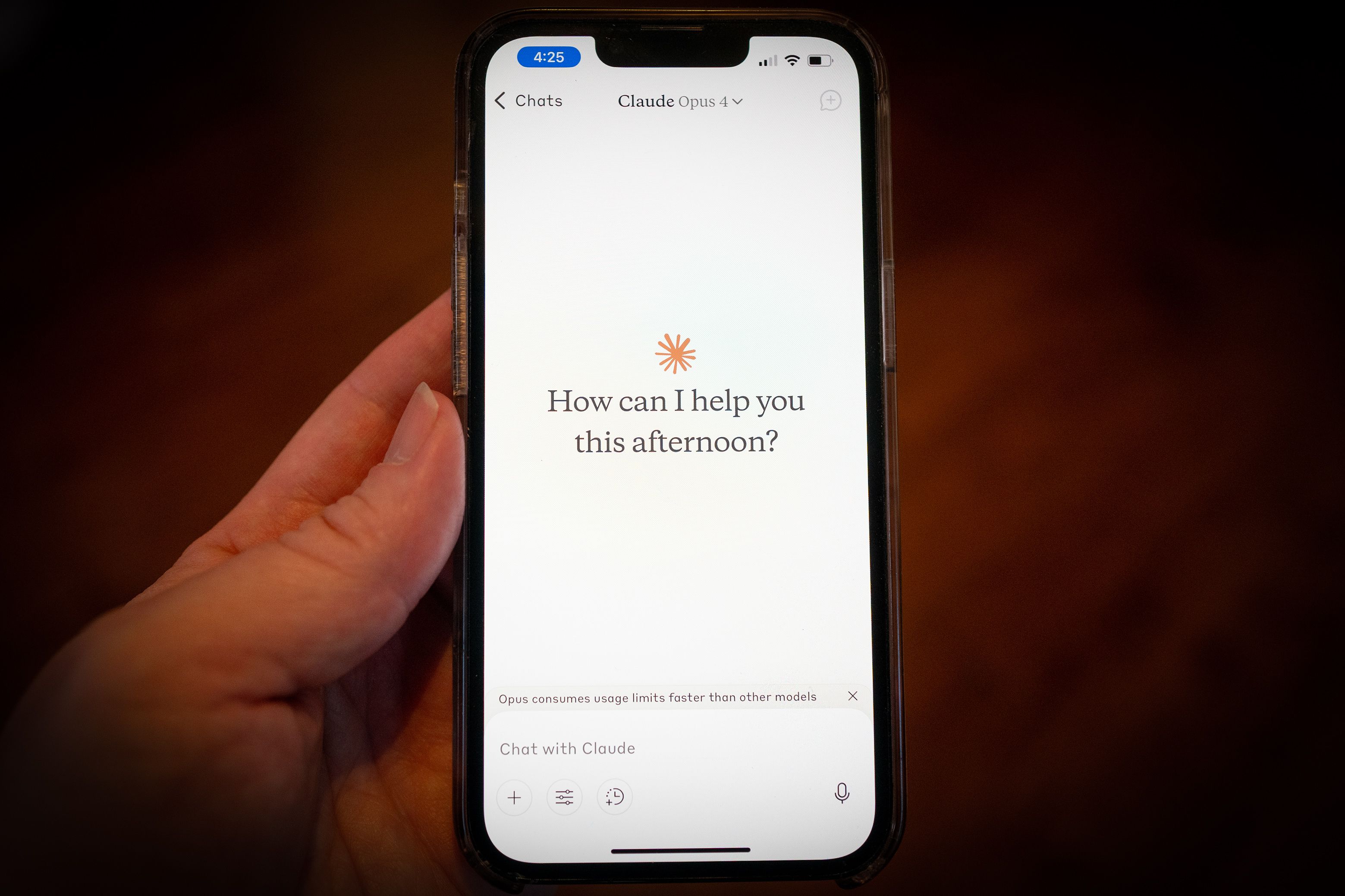 Photo of a hand holding a smartphone displaying a chat app interface asking “How can I help you this afternoon?”