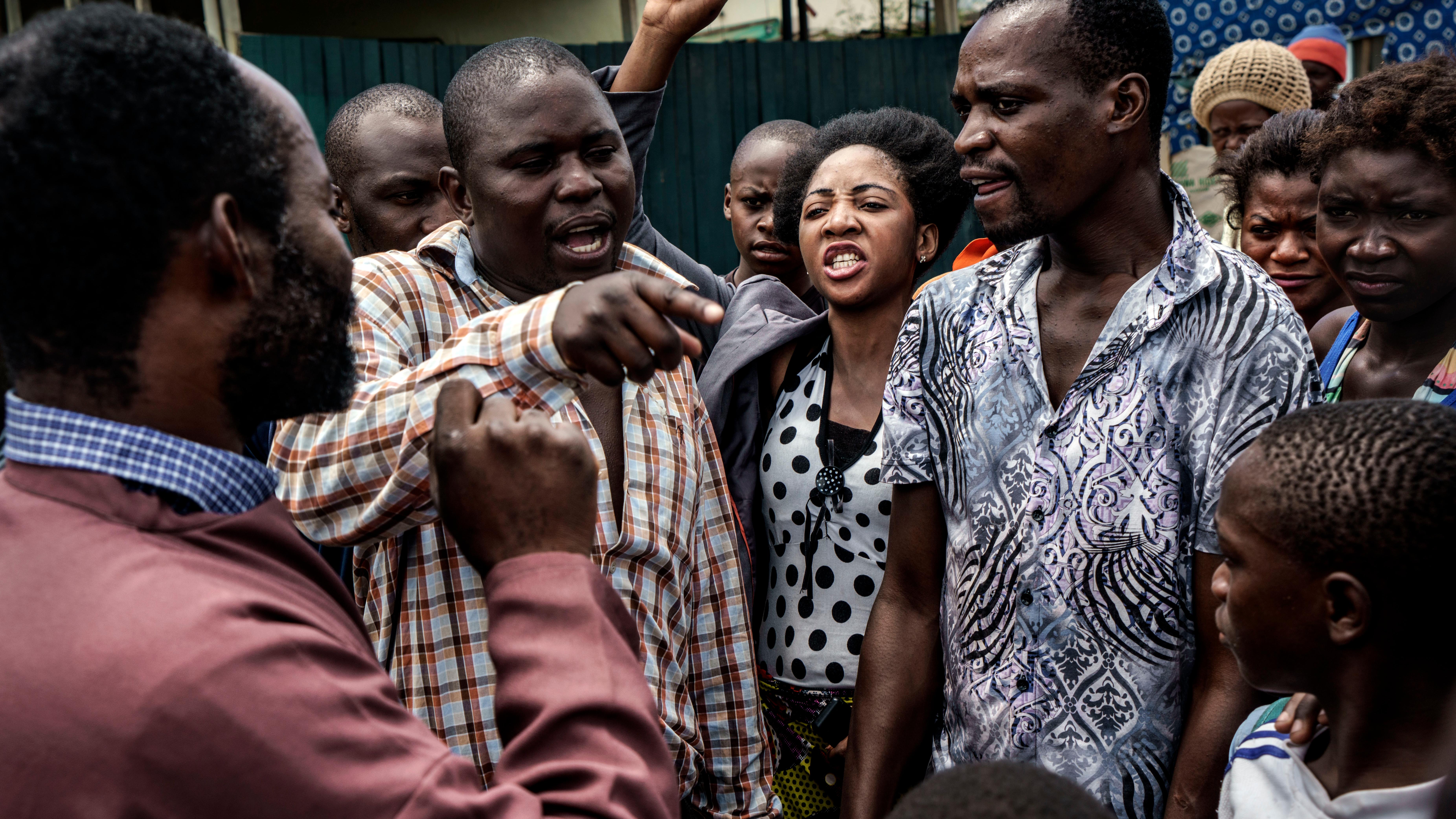 A group of people engaged in a heated discussion outdoors with diverse expressions and gestures.
