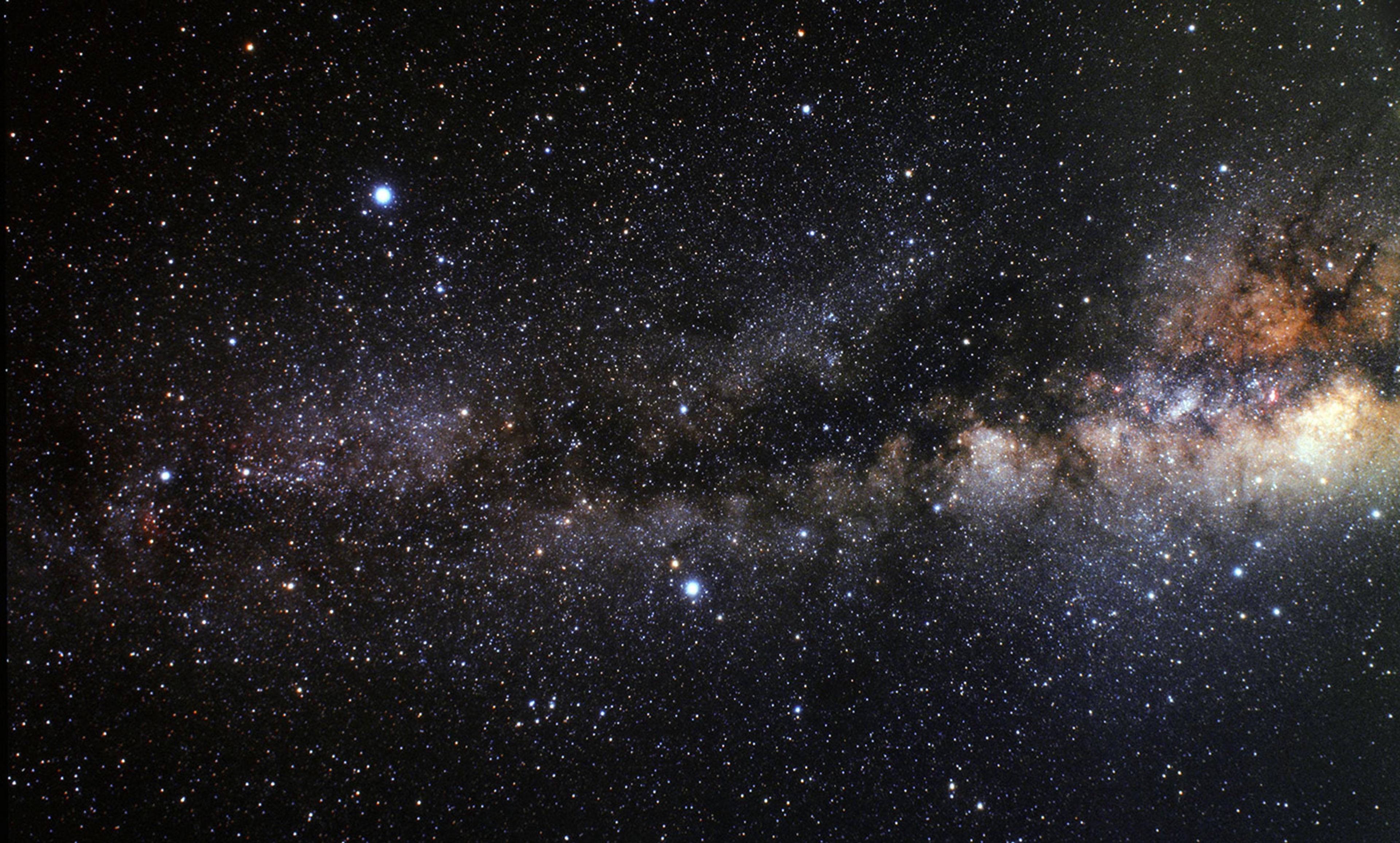 The Milky Way galaxy showing a dense field of stars, bright spots and dark clouds stretching across the night sky.