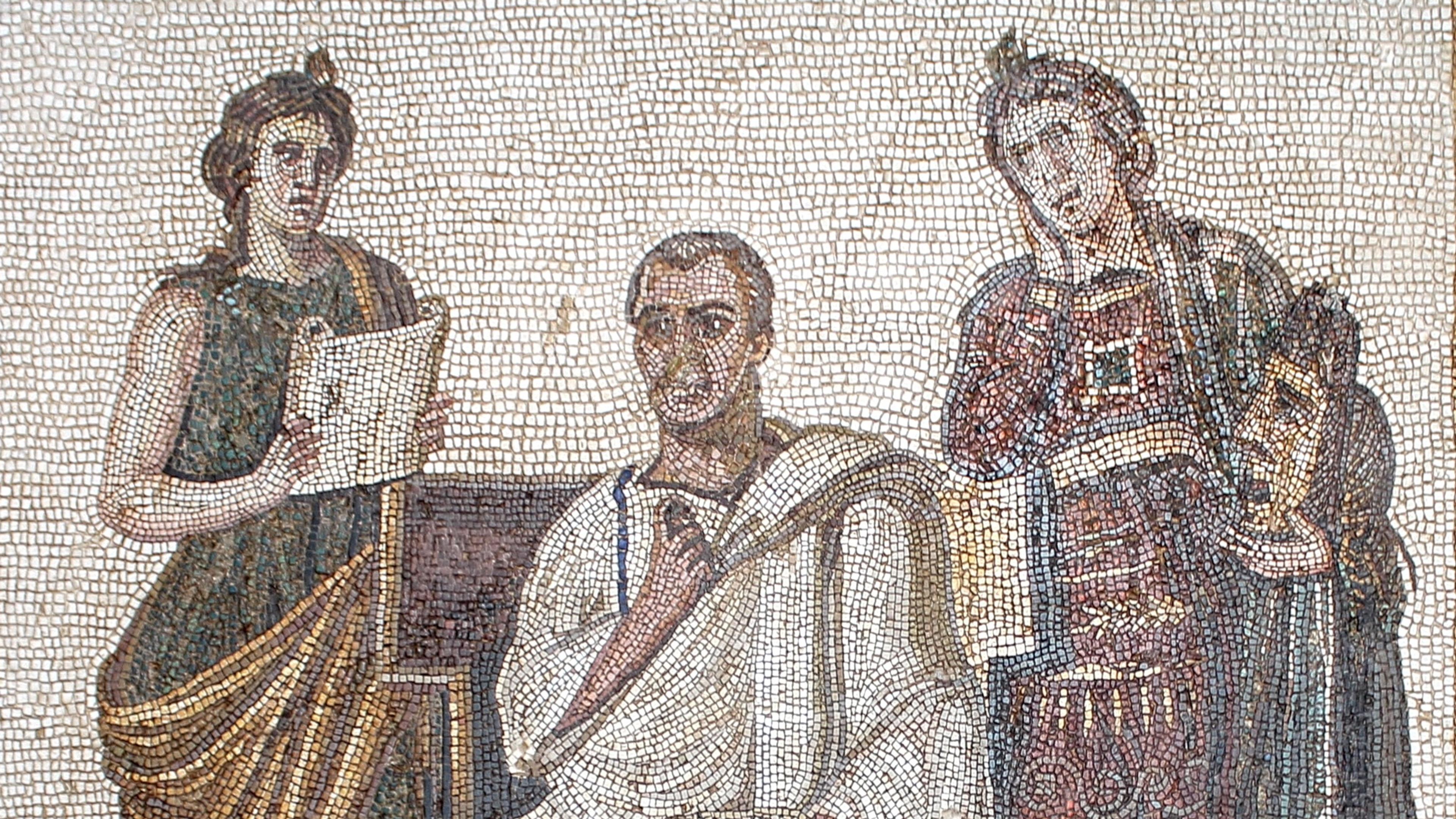 Ancient mosaic depicting a seated man and two standing figures, one holding a scroll, in a detailed Roman style scene.