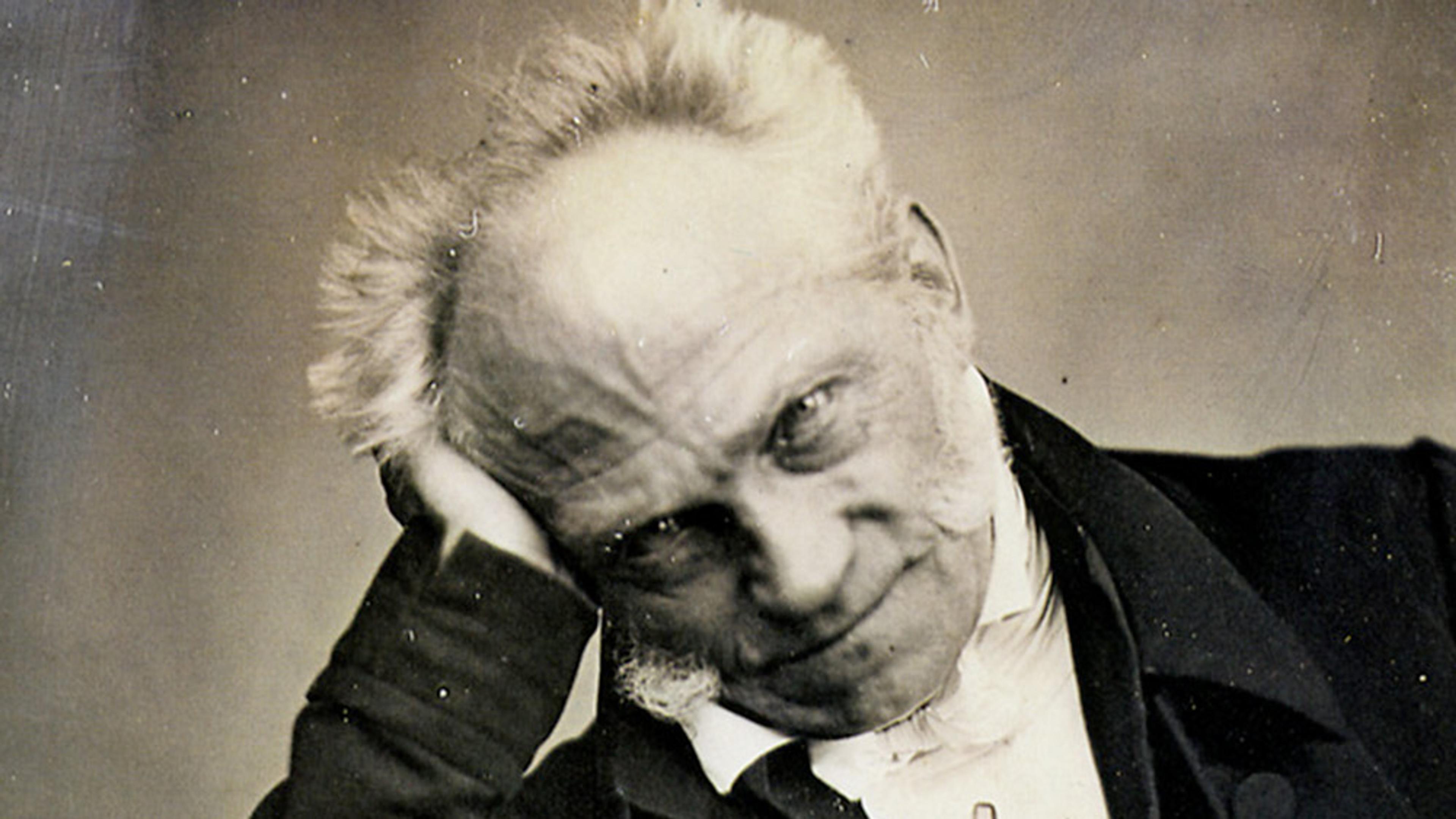 Vintage photo of Schopenhauer with white hair and mutton chops, resting his head on his hand and looking at the camera.