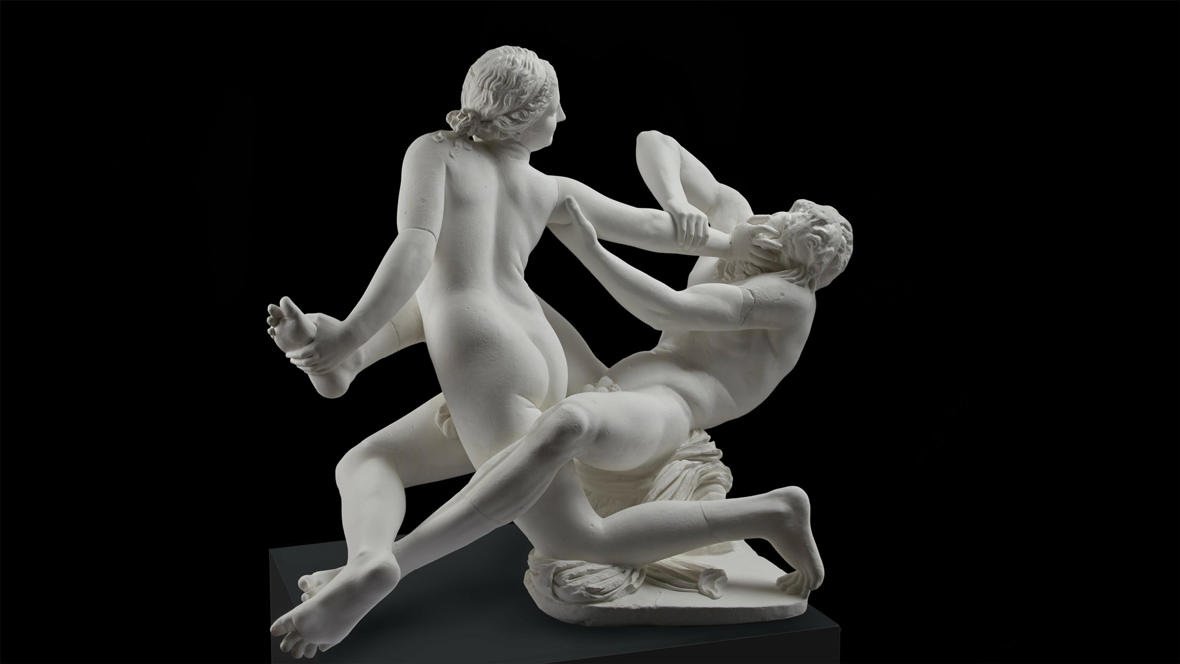 Marble sculpture of a dynamic struggle between two naked figures on a dark background, showcasing intricate details and movement.