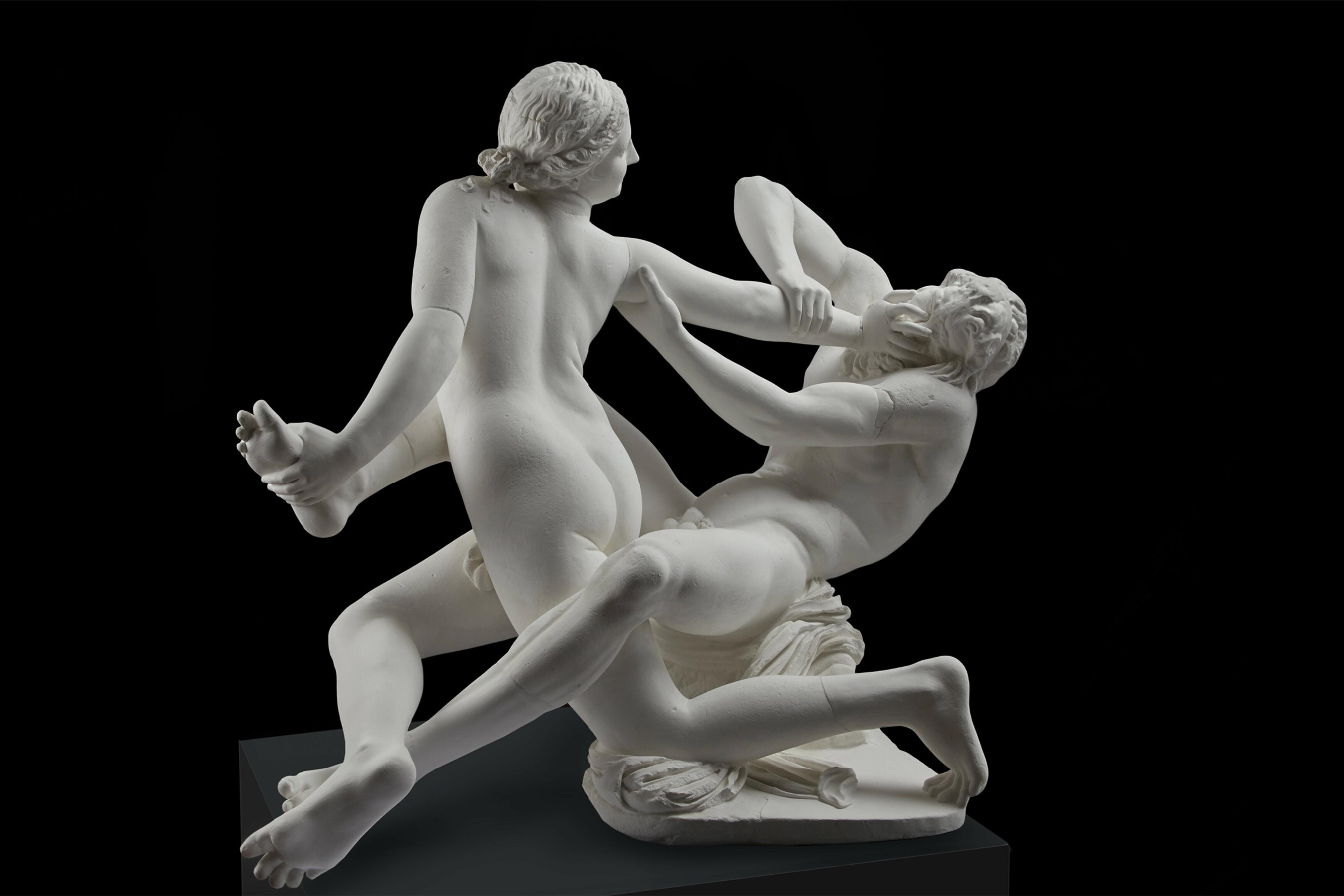 Marble sculpture of a dynamic struggle between two naked figures on a dark background, showcasing intricate details and movement.