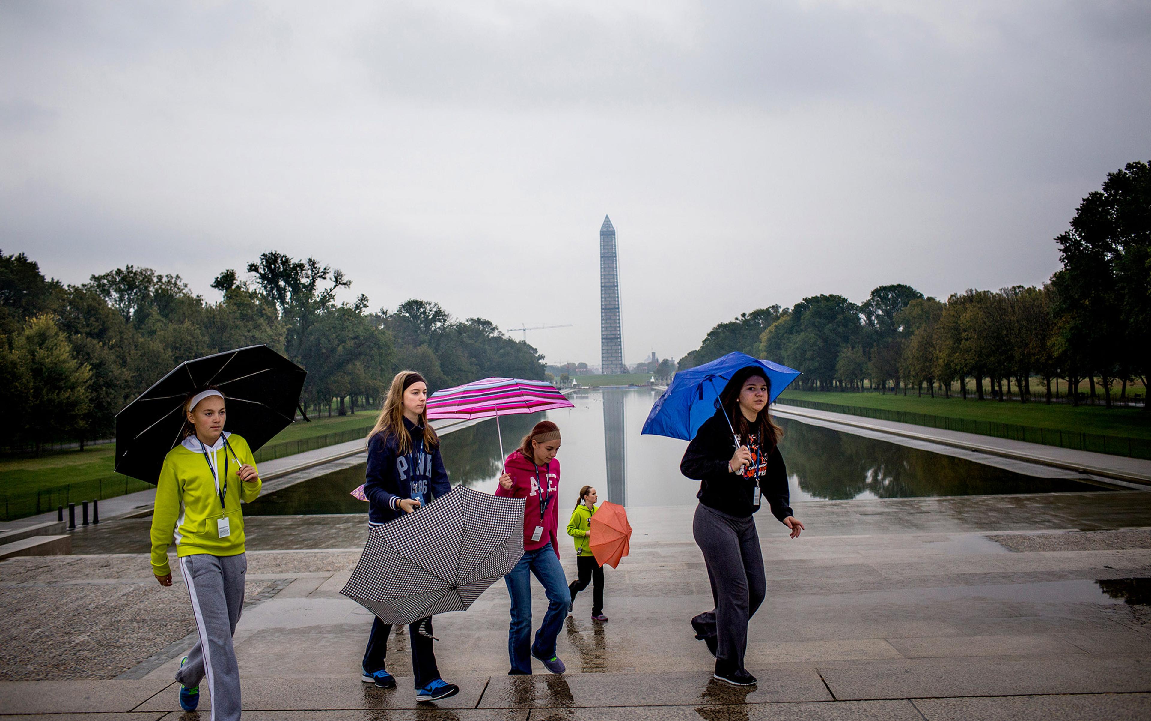 A group of girls walk past the Washington Monument on the National Mall in Washington, DC