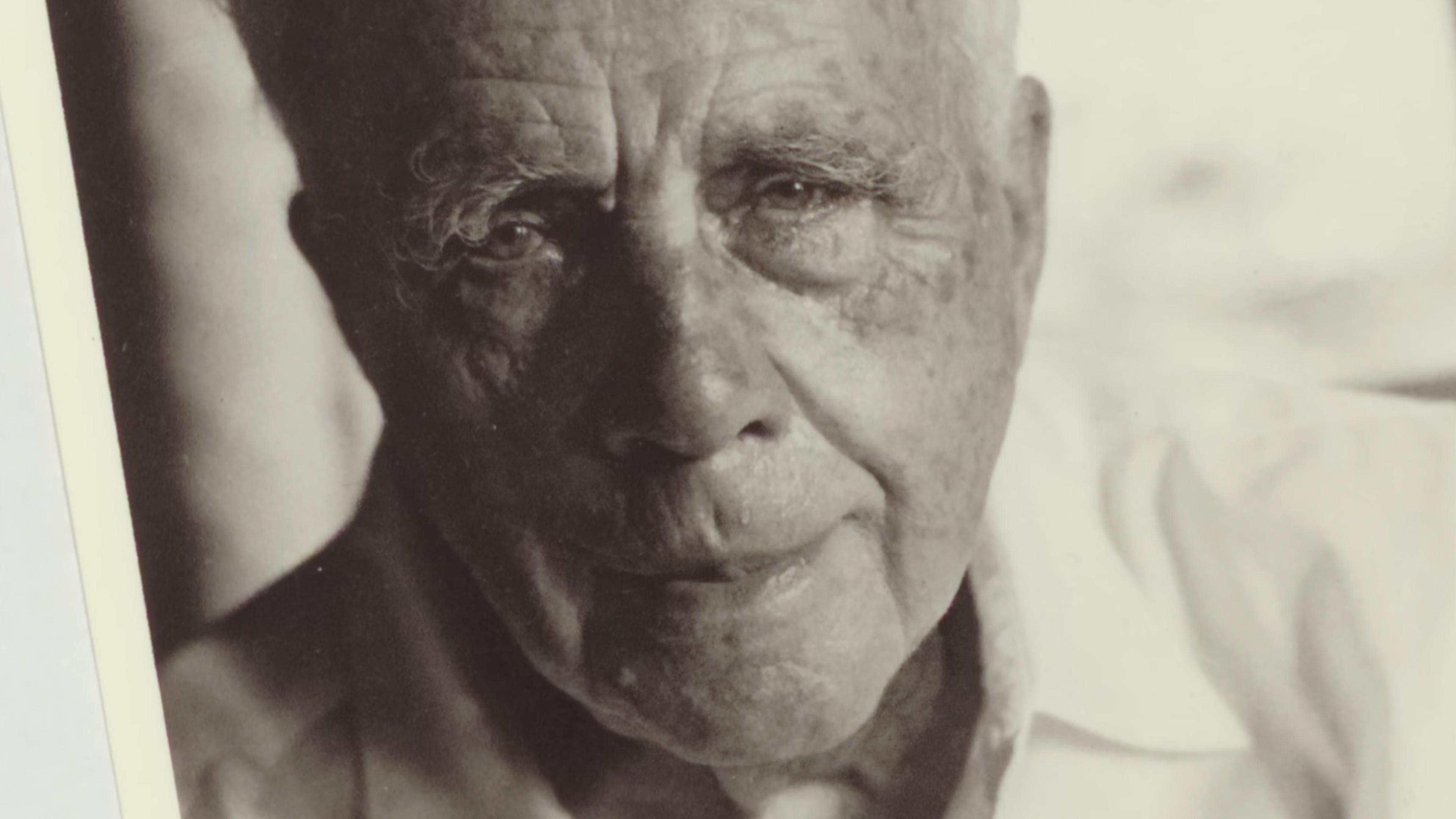 Black and white photo of an elderly man with a thoughtful expression wearing a light coloured shirt.