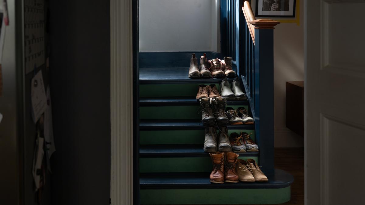 A dimly lit staircase with multiple pairs of shoes neatly arranged on each step.