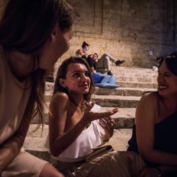 밤에 돌계단에서 세 명의 여성이 이야기를 나누고 웃고 있고, 그 배경에는 사람들이 휴식을 취하고 있는 모습이다.<BR>