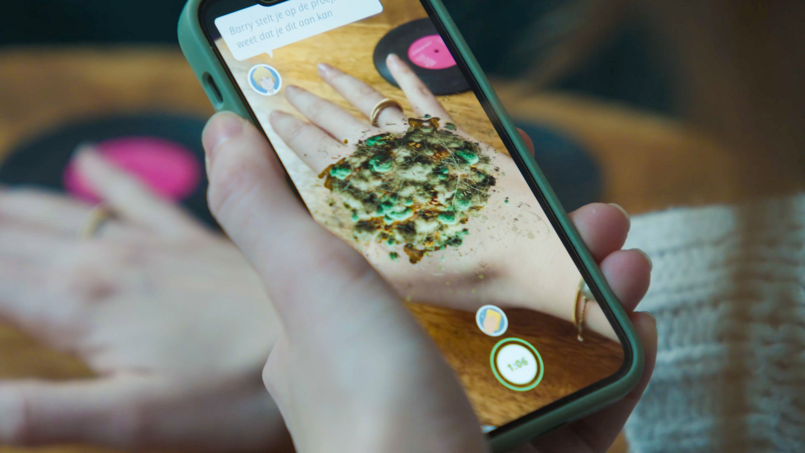 Photo of a smartphone displaying an augmented reality app showing a textured object over a hand on the screen.