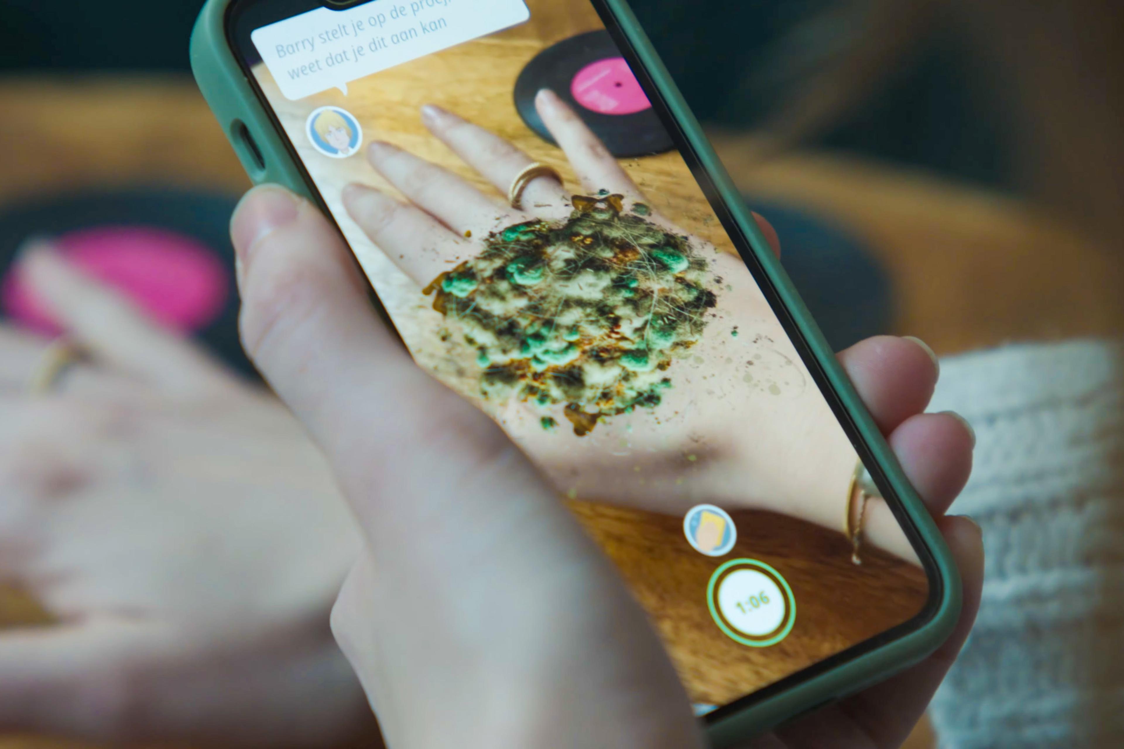 Photo of a smartphone displaying an augmented reality app showing a textured object over a hand on the screen.