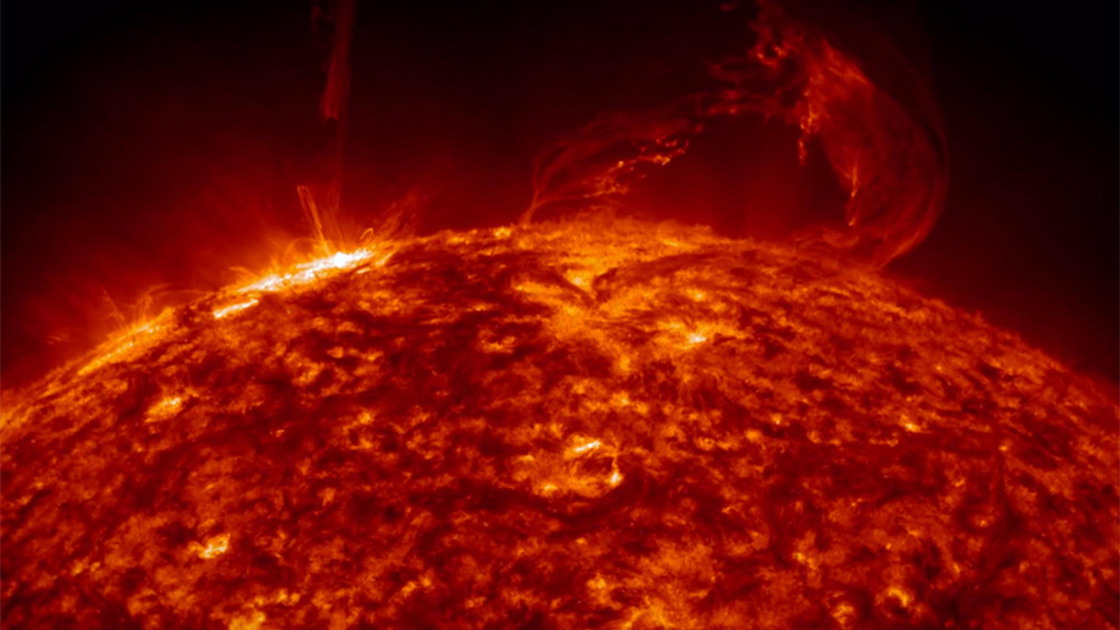 The Sun’s fiery surface, with intense solar flares and prominences with bright, glowing, swirling patterns.