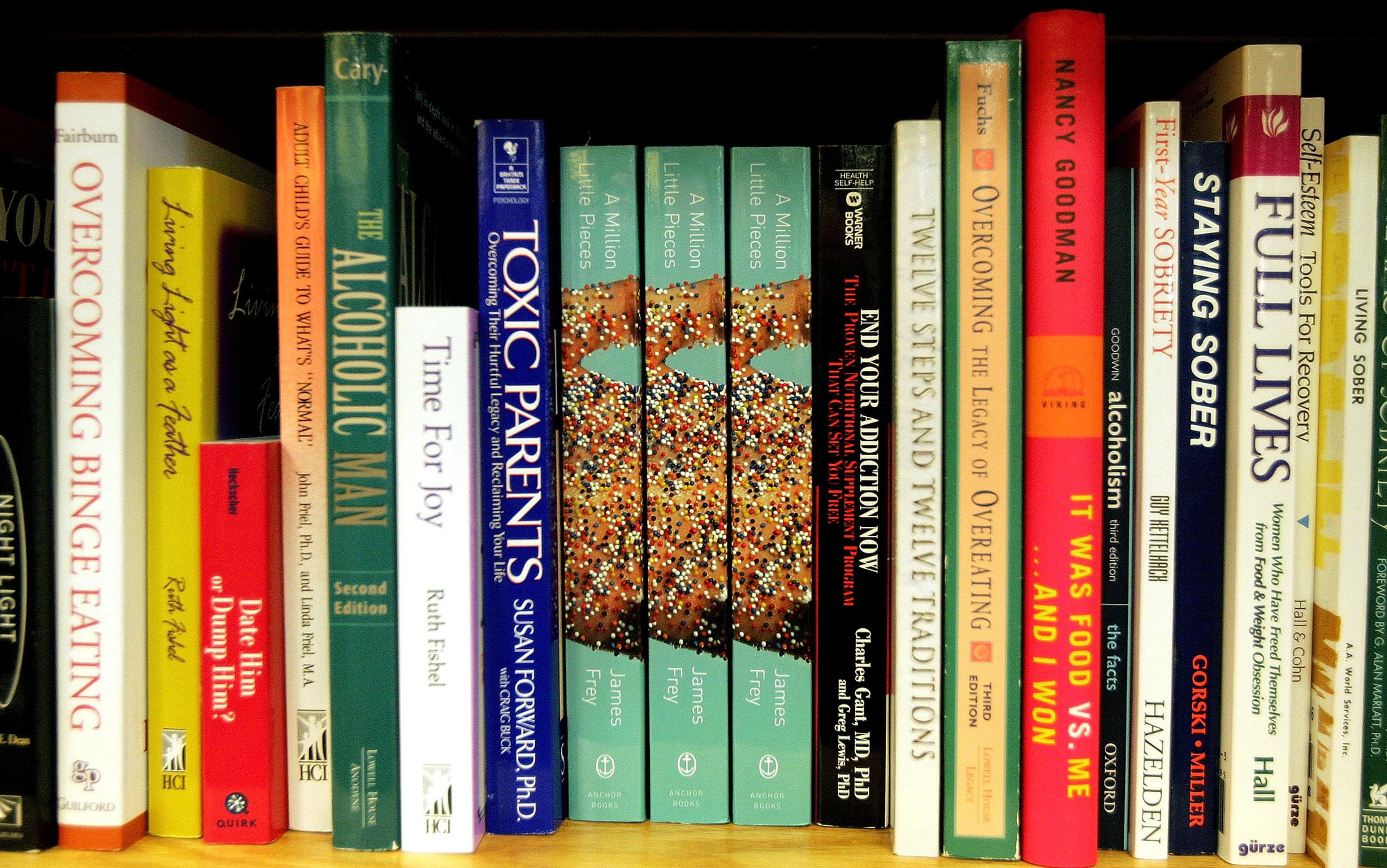 A shelf filled with self-help books on addiction, eating disorders and mental health, including titles like “Overcoming Binge Eating.”