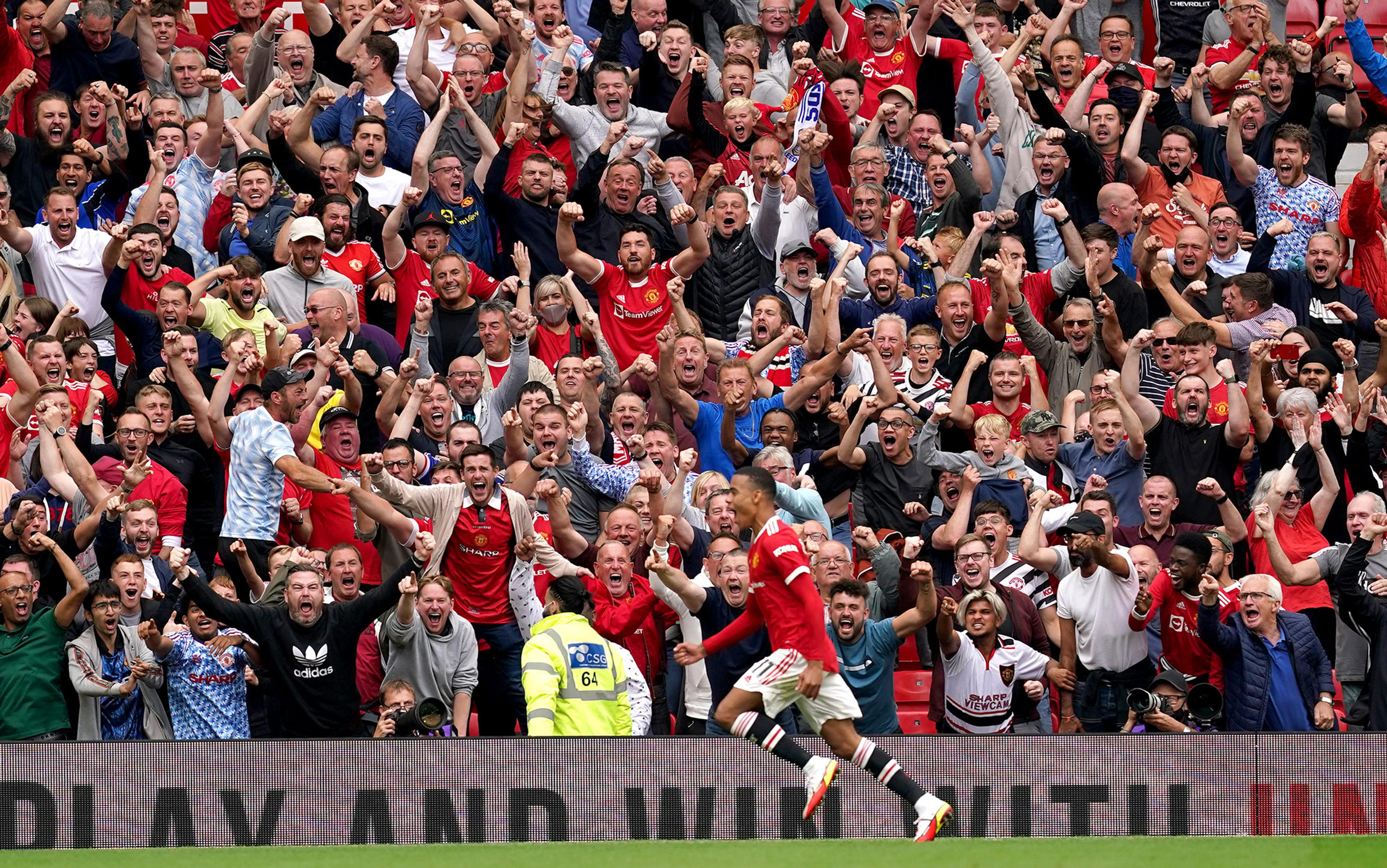 A footballer in the Manchester United red strip runs past cheering fans in the stadium