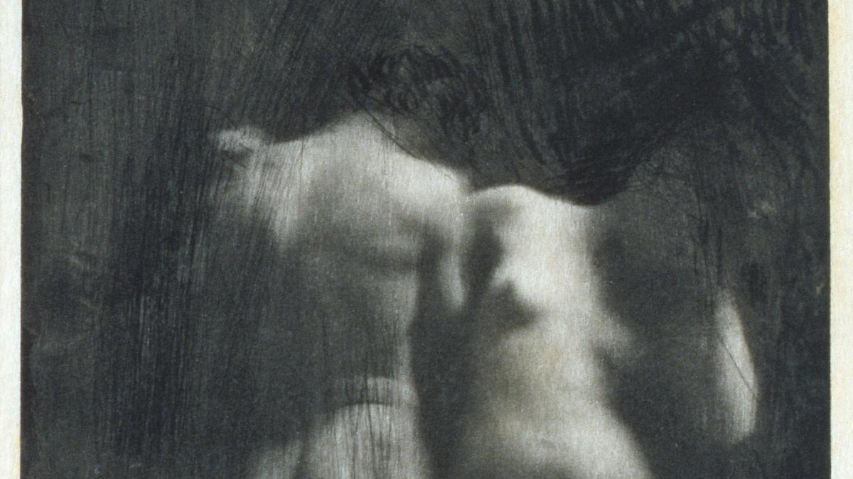Blurry monochrome photograph of two intertwined nude bodies in an ethereal style.