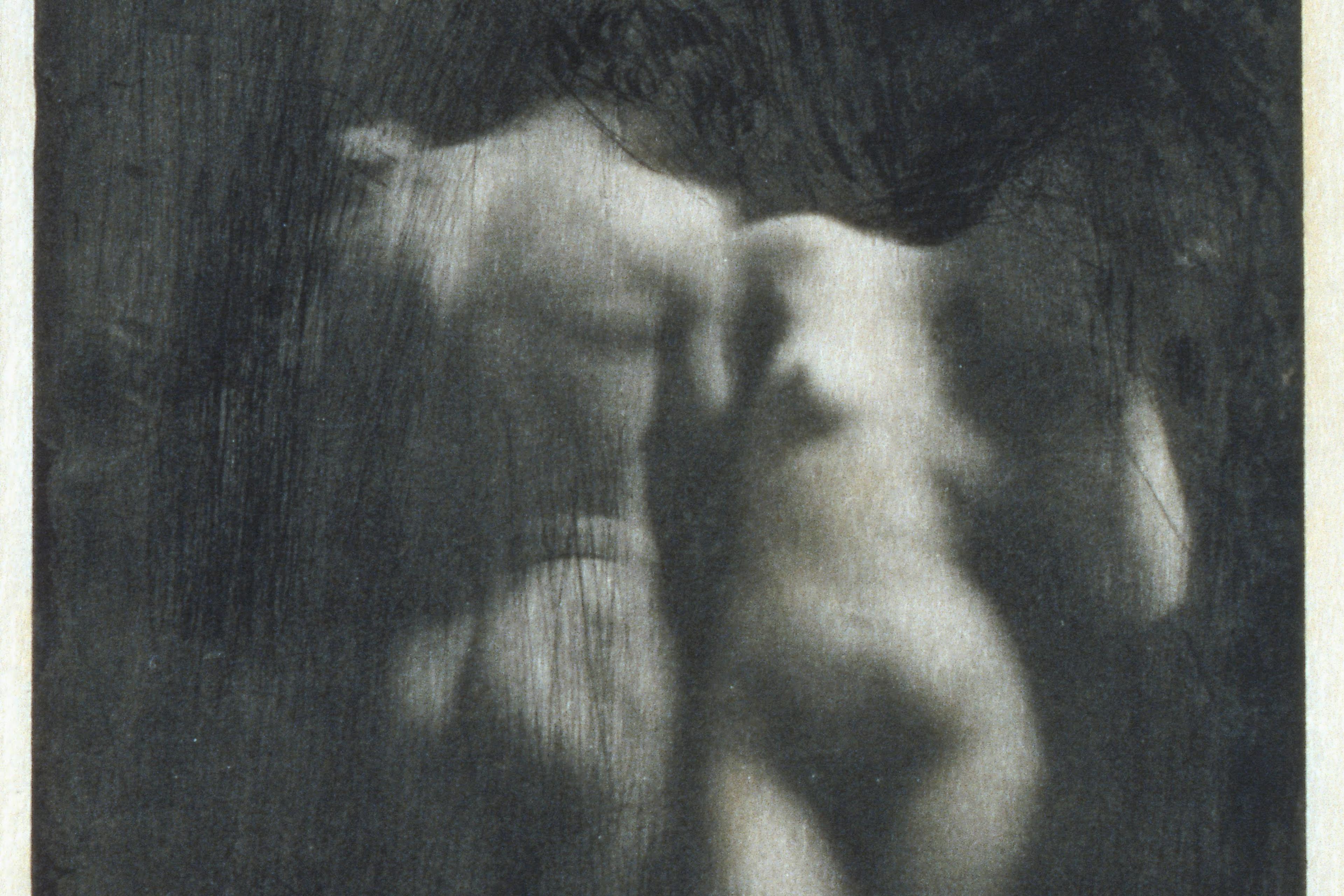 Blurry monochrome photograph of two intertwined nude bodies in an ethereal style.