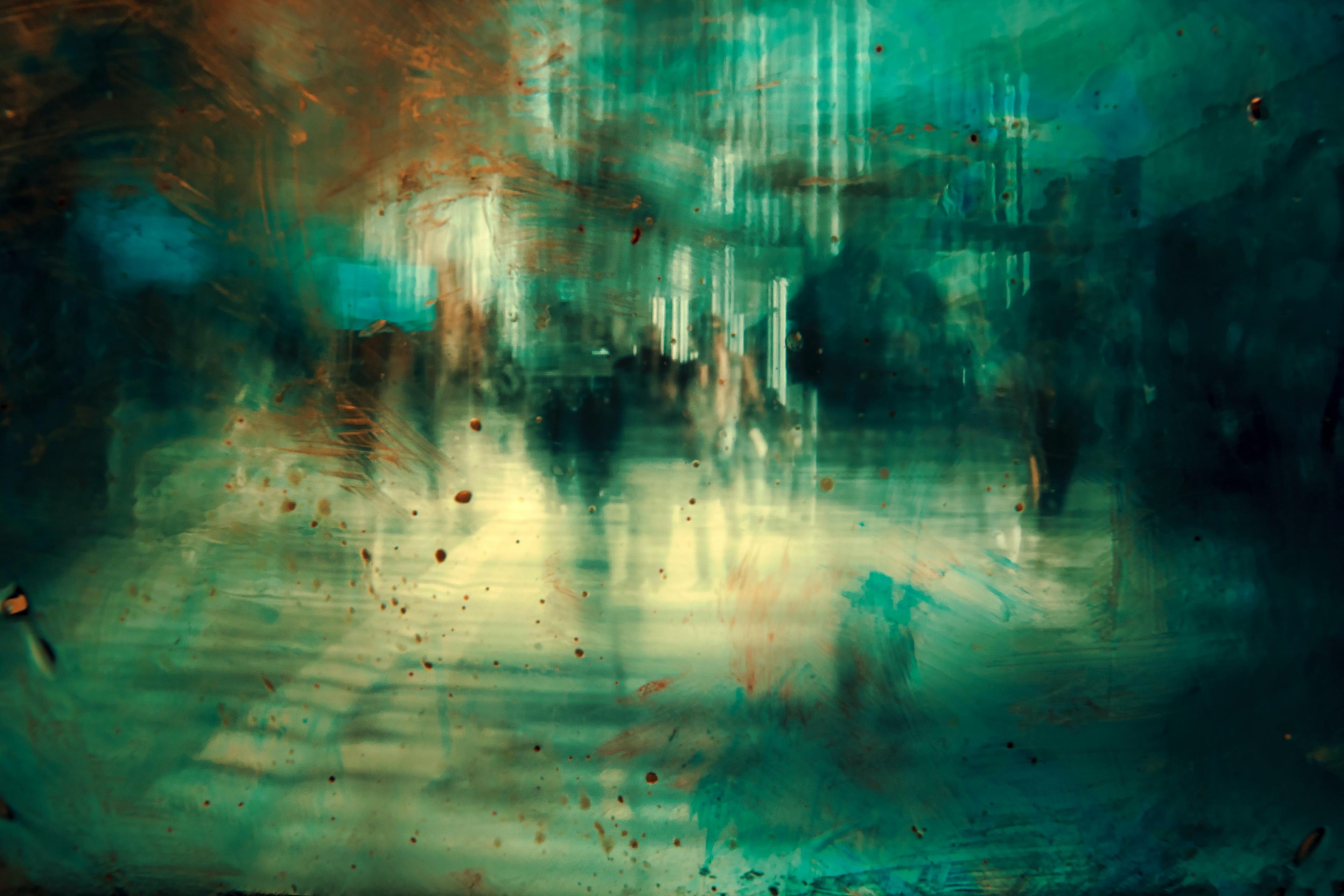 Abstract painting of a blurred urban scene with teal and orange hues depicting moving silhouettes in a cityscape.