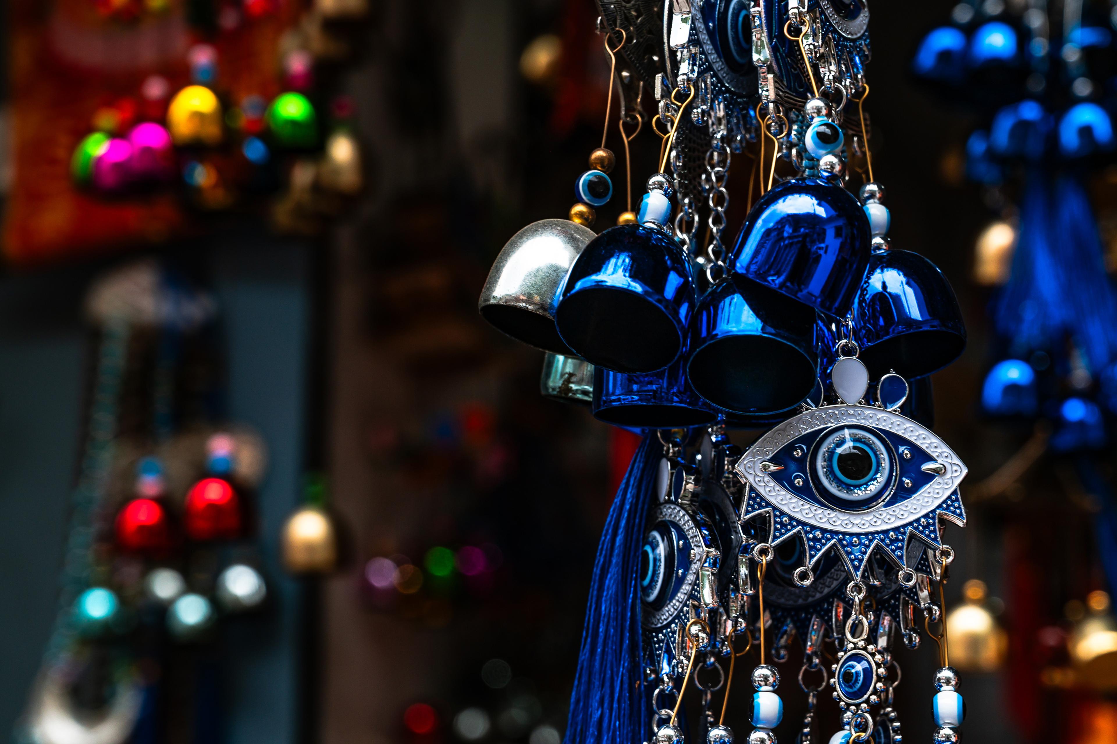 Colourful evil eye charms and blue metal bells hanging together with a blurred background.