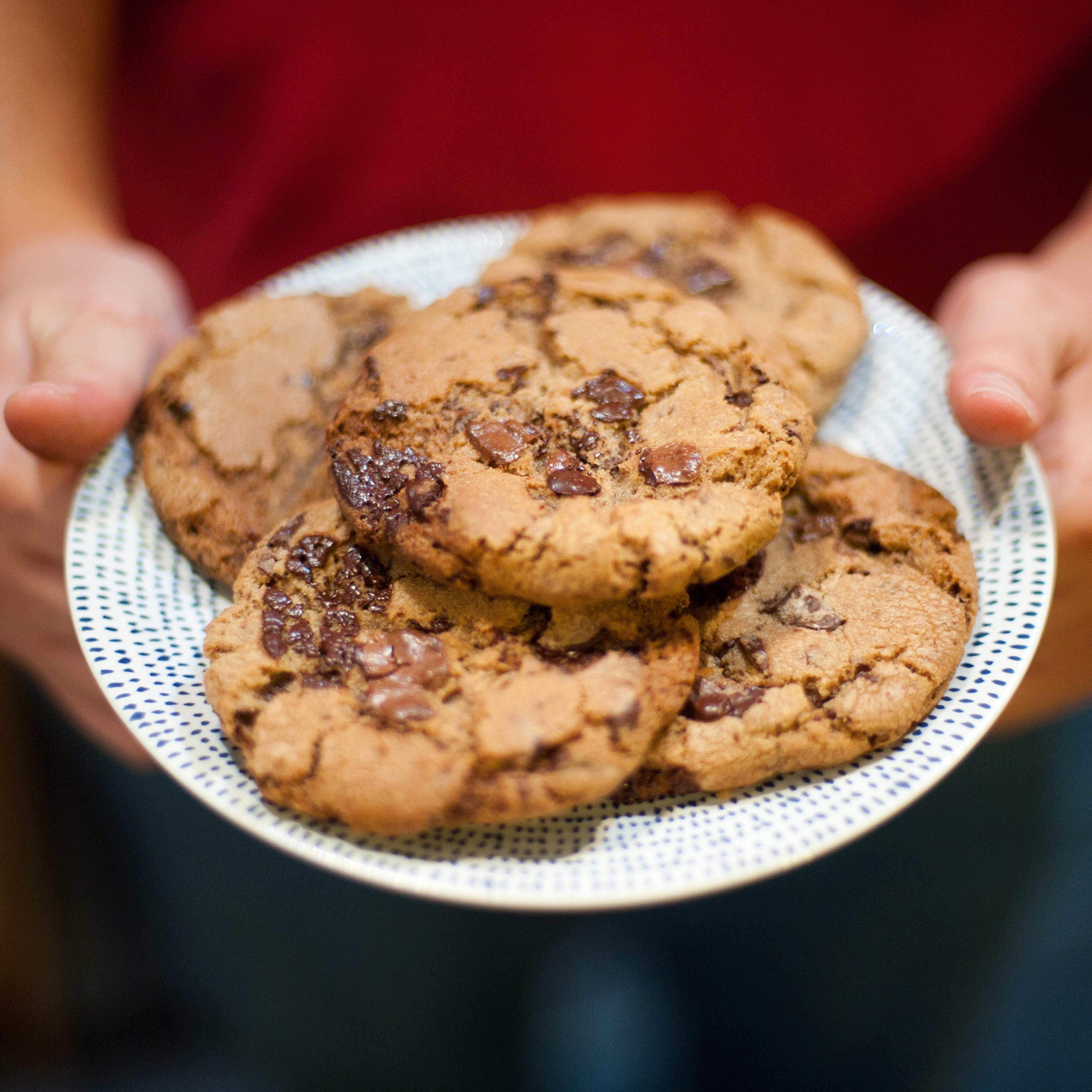 A child is offering a plate of homemade cookies