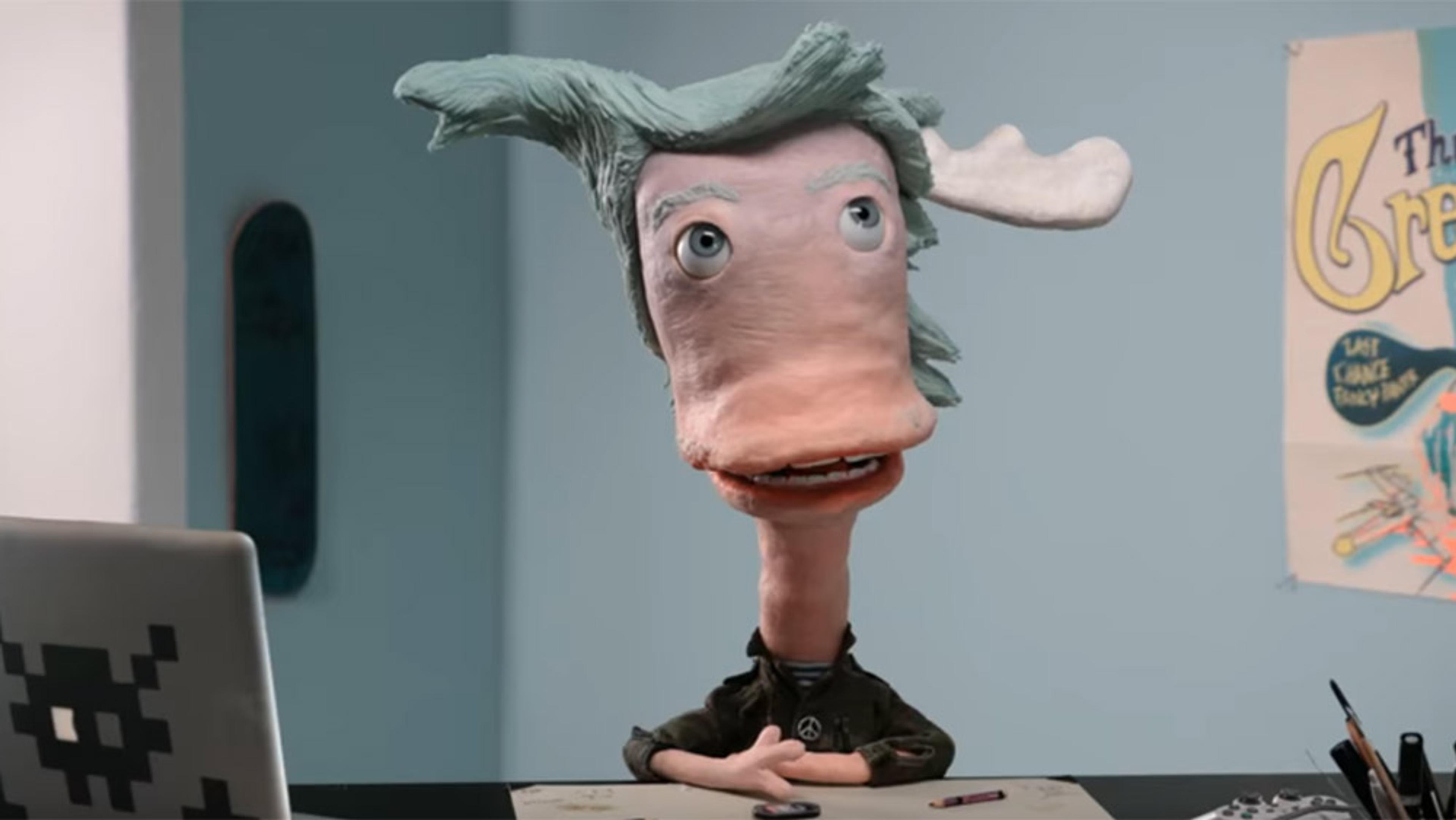Claymation character with blue hair and large head at a desk with a laptop in an office setting, with posters on the wall behind.