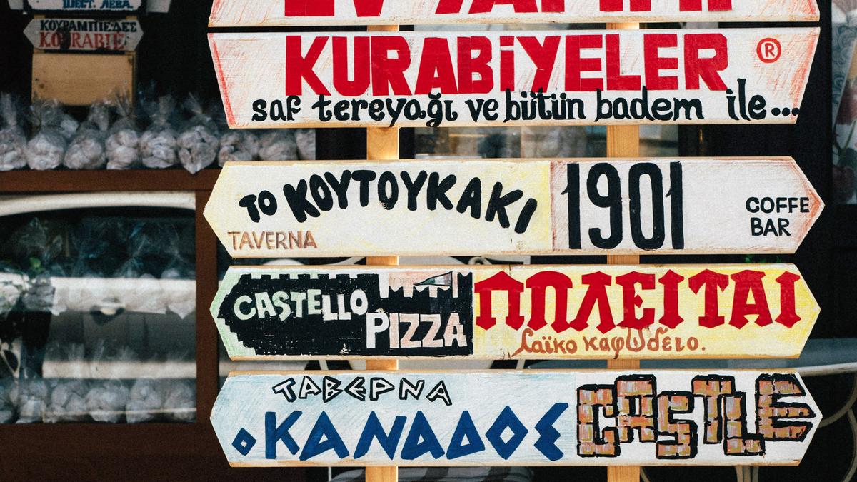 Photo of colourful wooden signs with various text in different languages outside a shop or cafe.