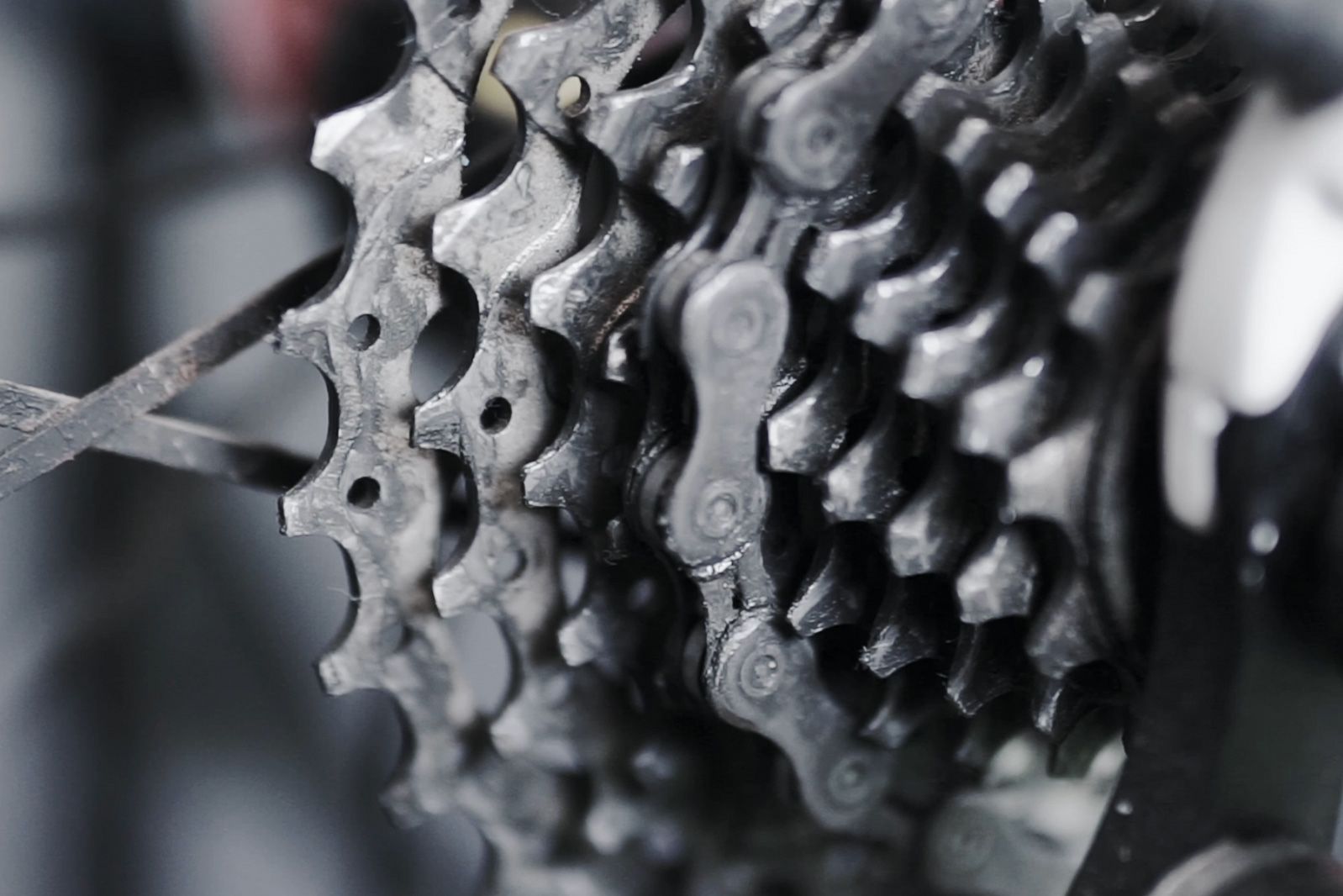 Close-up video of a bicycle gear cassette with chain in movement, showing detailed metal texture and mechanical design.