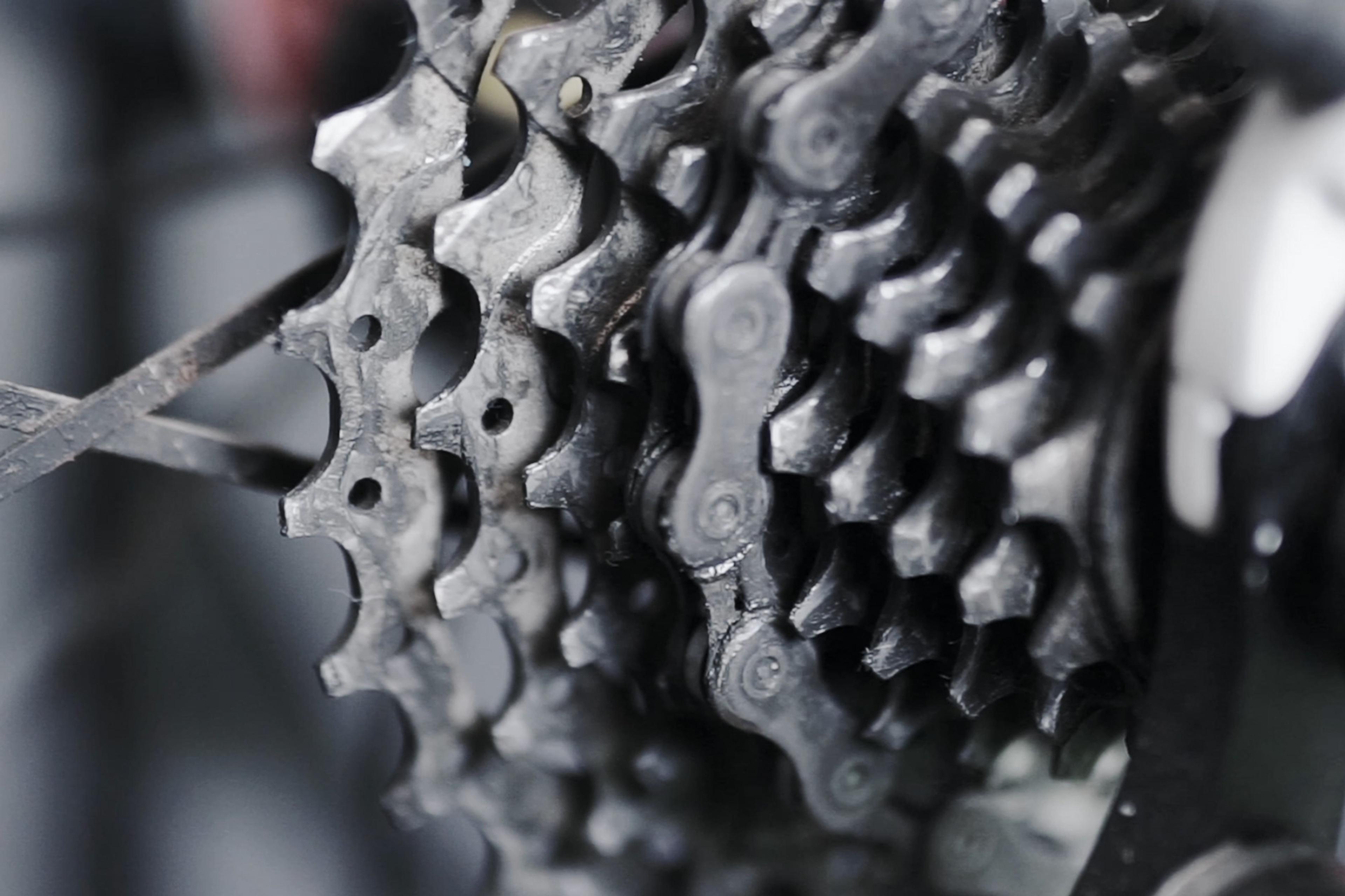 Close-up video of a bicycle gear cassette with chain in movement, showing detailed metal texture and mechanical design.