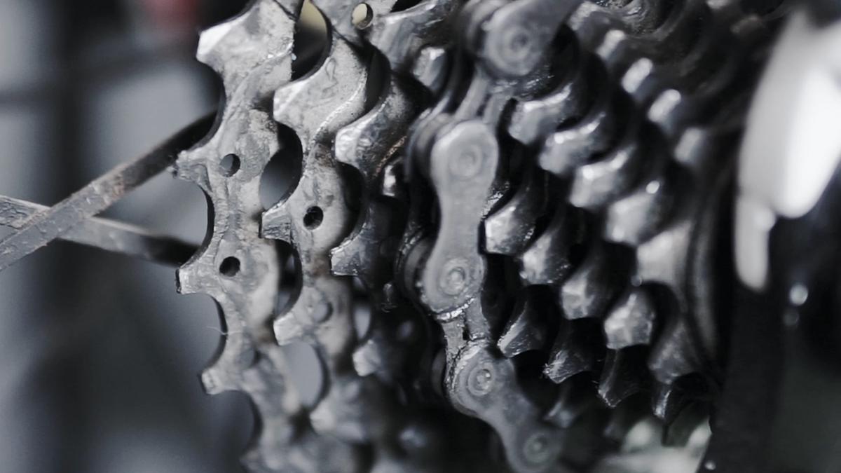 Close-up video of a bicycle gear cassette with chain in movement, showing detailed metal texture and mechanical design.