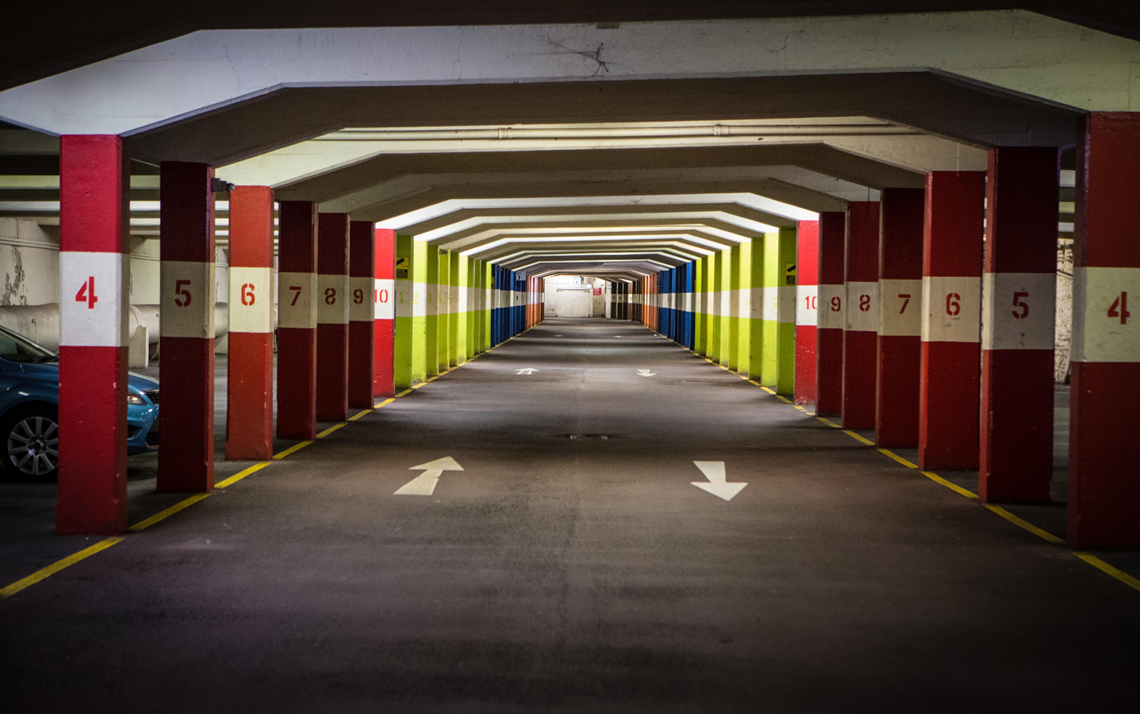 A colourful underground car park with numbered pillars and painted lanes with directional arrows.