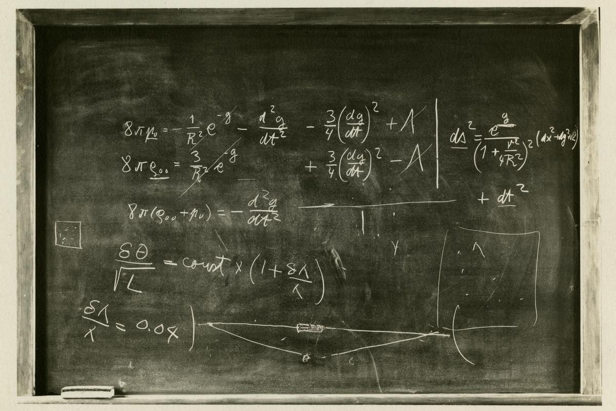 Black and white photo of a chalkboard filled with complex mathematical equations and diagrams.