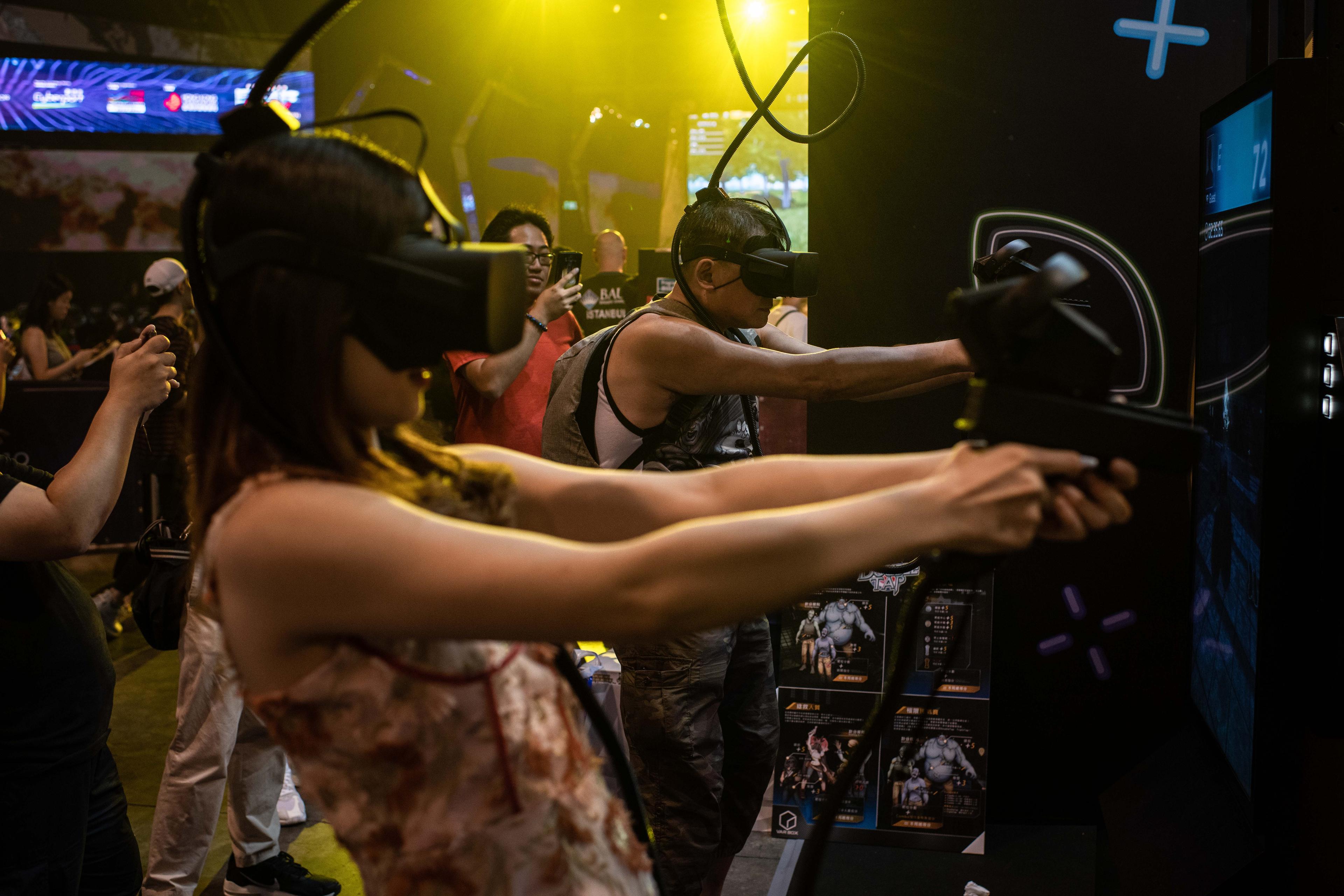 Photo of people using virtual reality headsets and controllers at a gaming event with a vibrant yellow background.