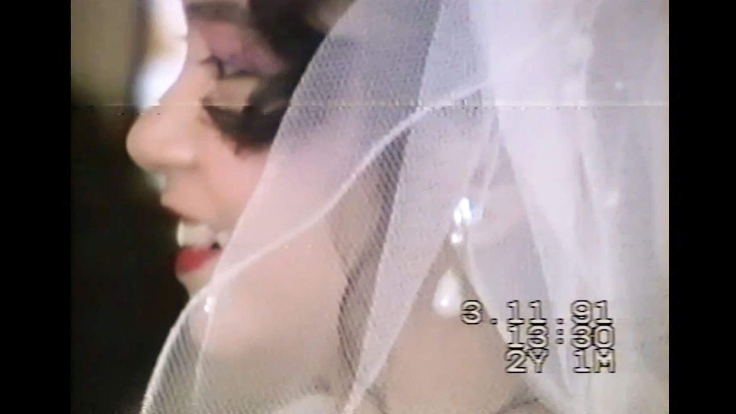 Photo of a bride in profile with a veil smiling, timestamp from 1991 visible on the image.