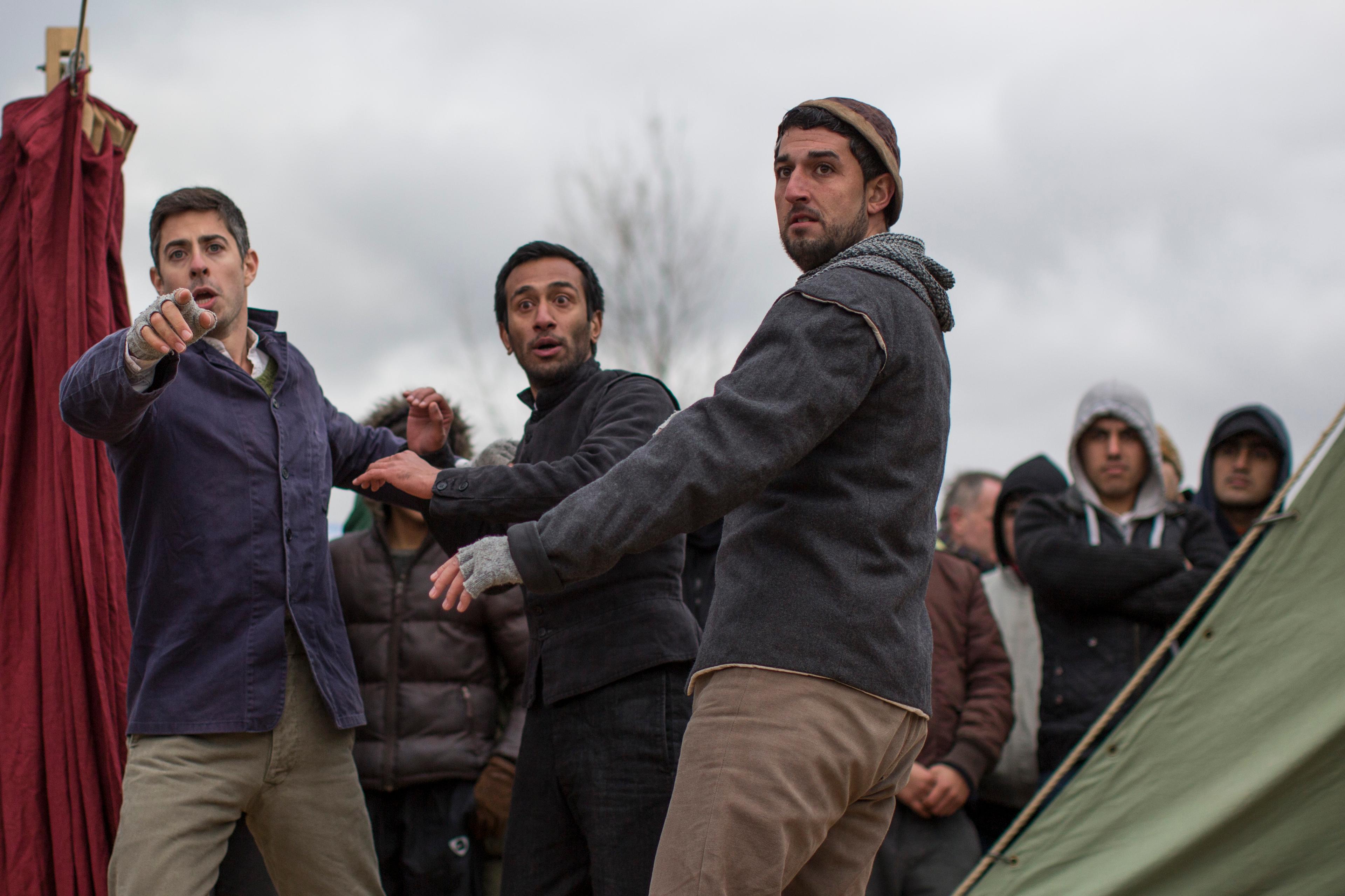 Photo of three men in jackets and beanies looking intently, with a group of people in the background on a cloudy day.